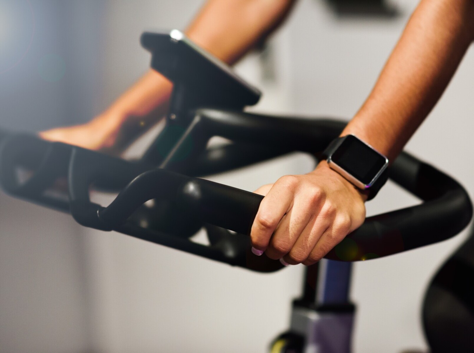 close-up of a woman’s hands using a stationary bike for cardio to improve her yoga and weight loss results