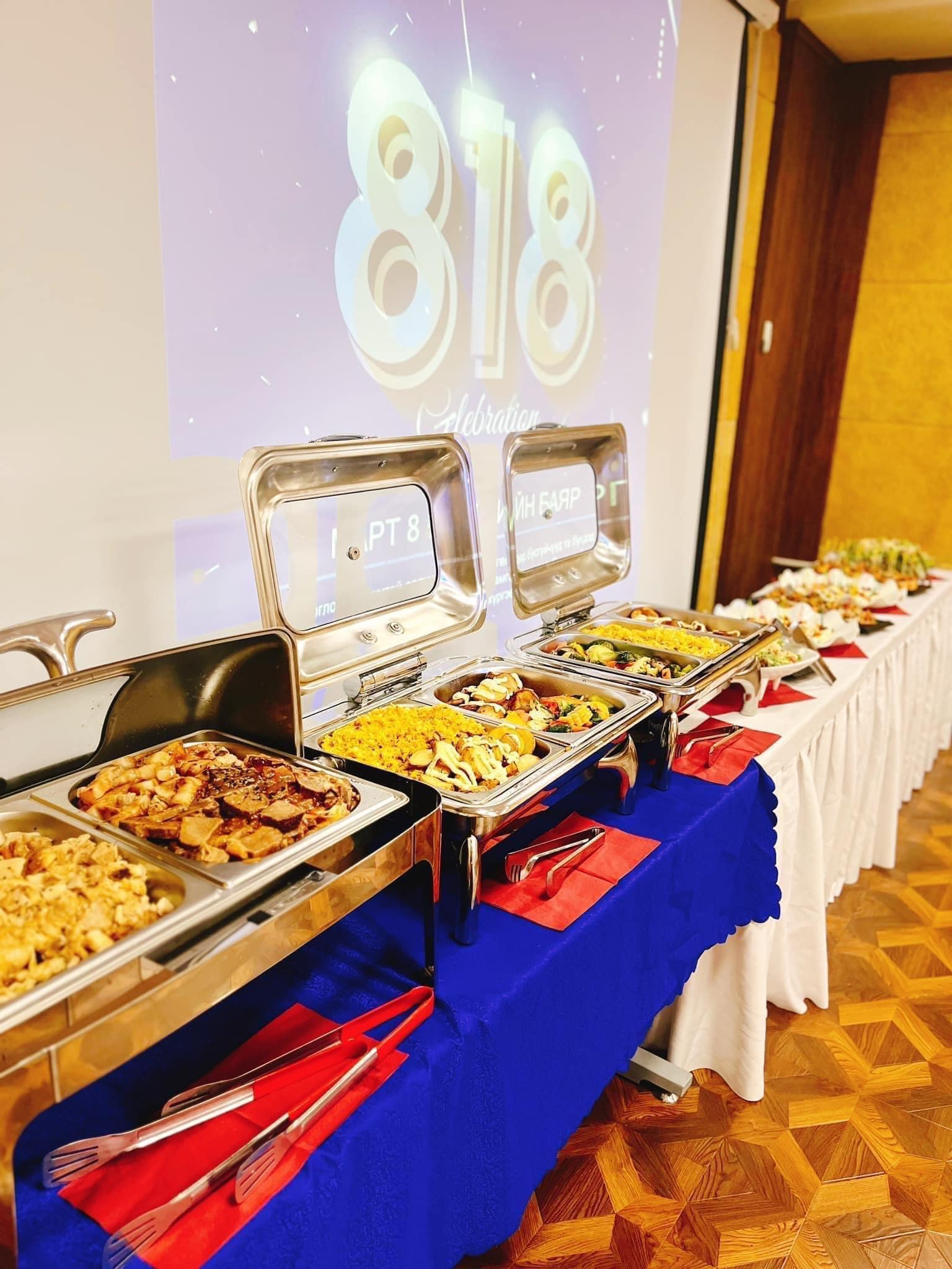 A smiling young man with crossed arms, wearing a plaid shirt and white t-shirt, poses against a dark background.