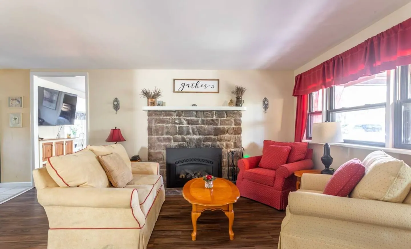 Living room with cream sofas, red armchair and stone gas fireplace at Relax in Style