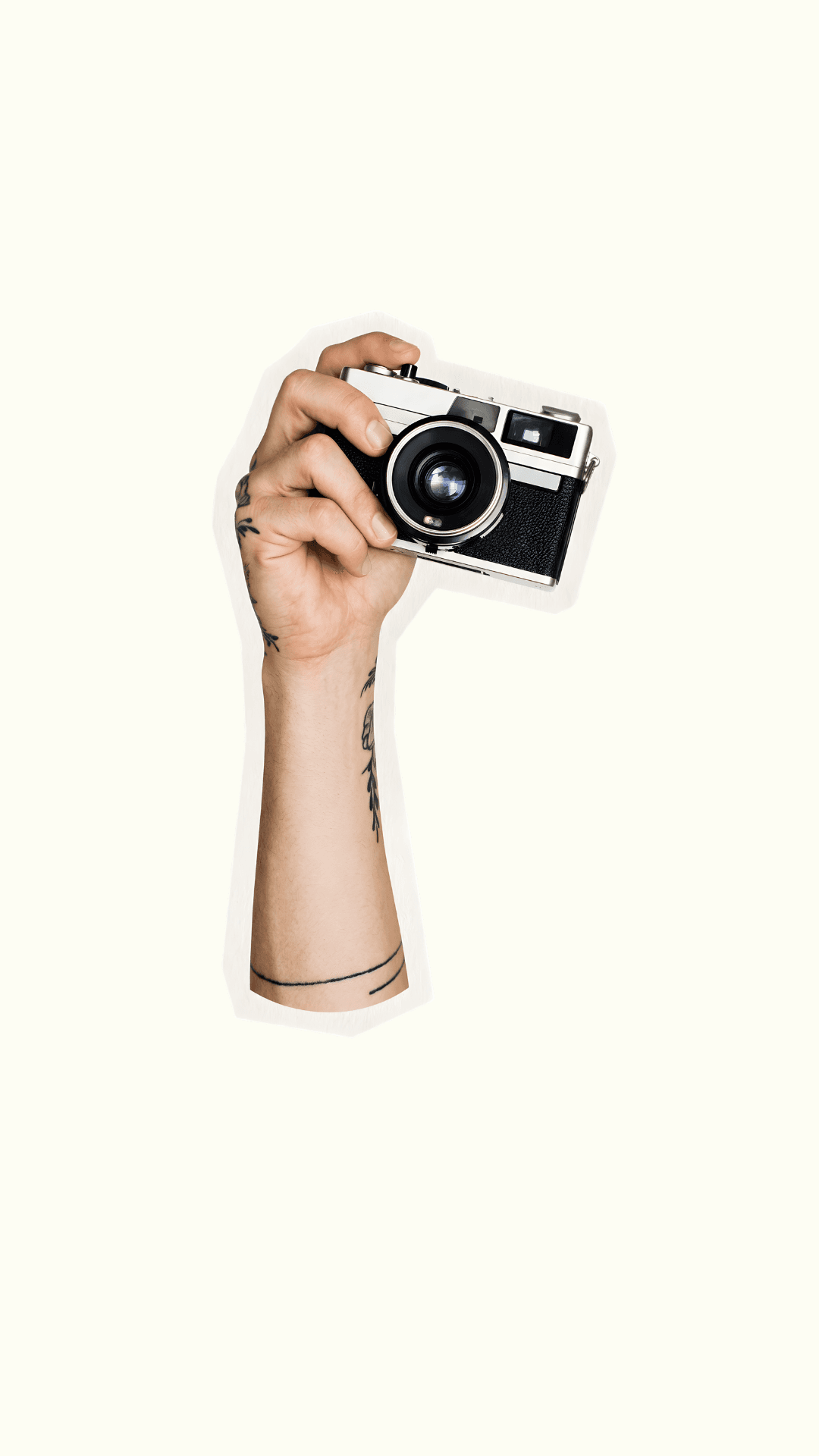 Tattooed hand holding a vintage film camera against a cream background