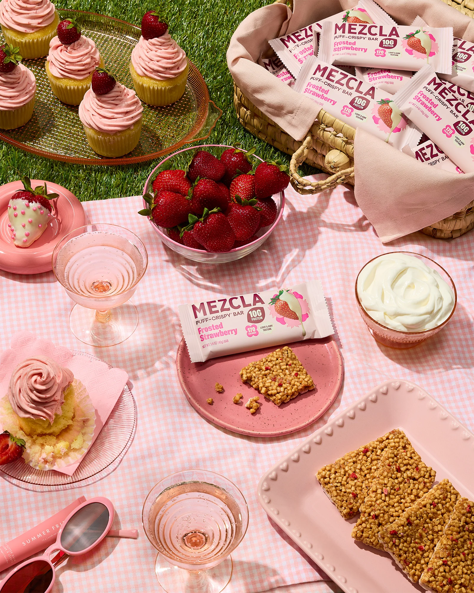 Mezcla Frosted Strawberry protein bars at a pink picnic with cupcakes, fresh strawberries and rose