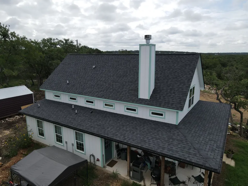 Dark architectural shingles on a San Antonio farmhouse; illustrative completed roof, not a documented cold-weather installation.