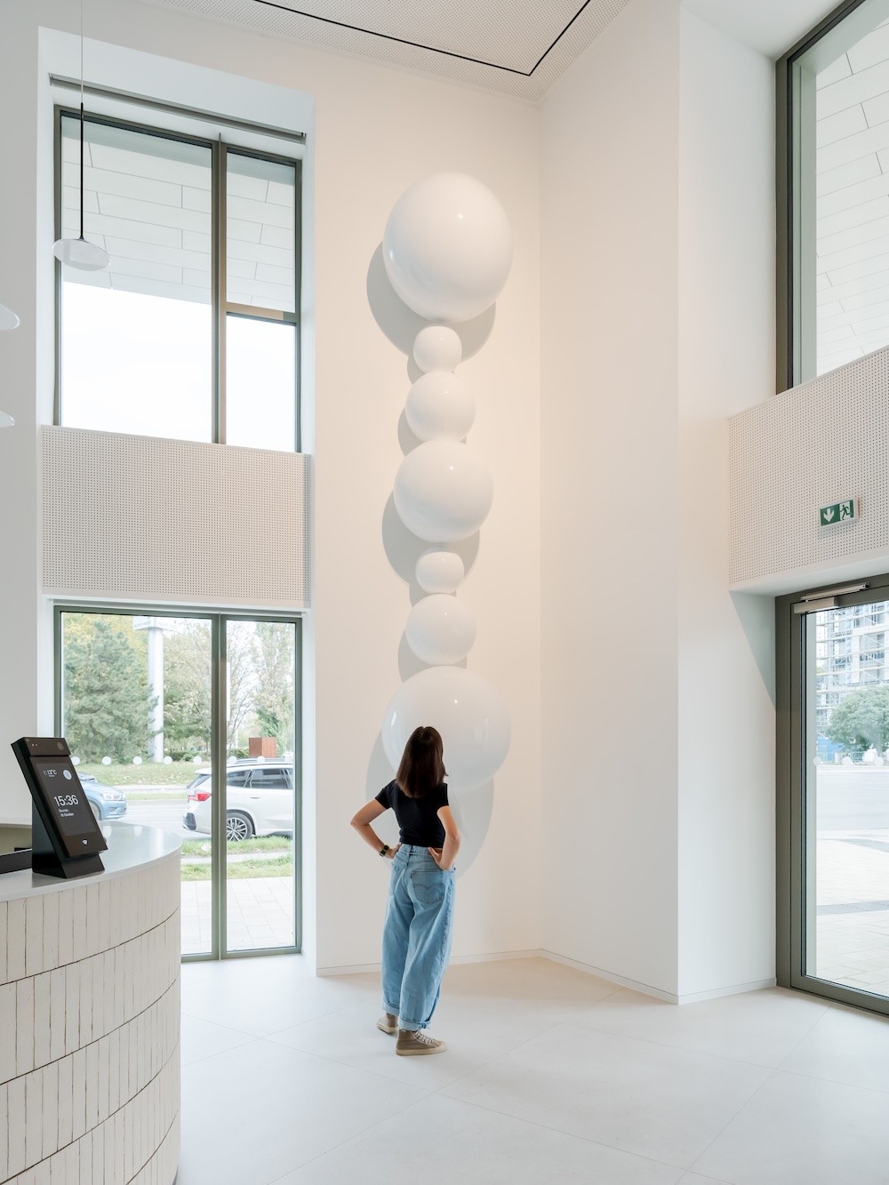 Žlté smiley objekty z vlny visiace v bielom galériovom priestore – dielo Niny A. Šoškovej