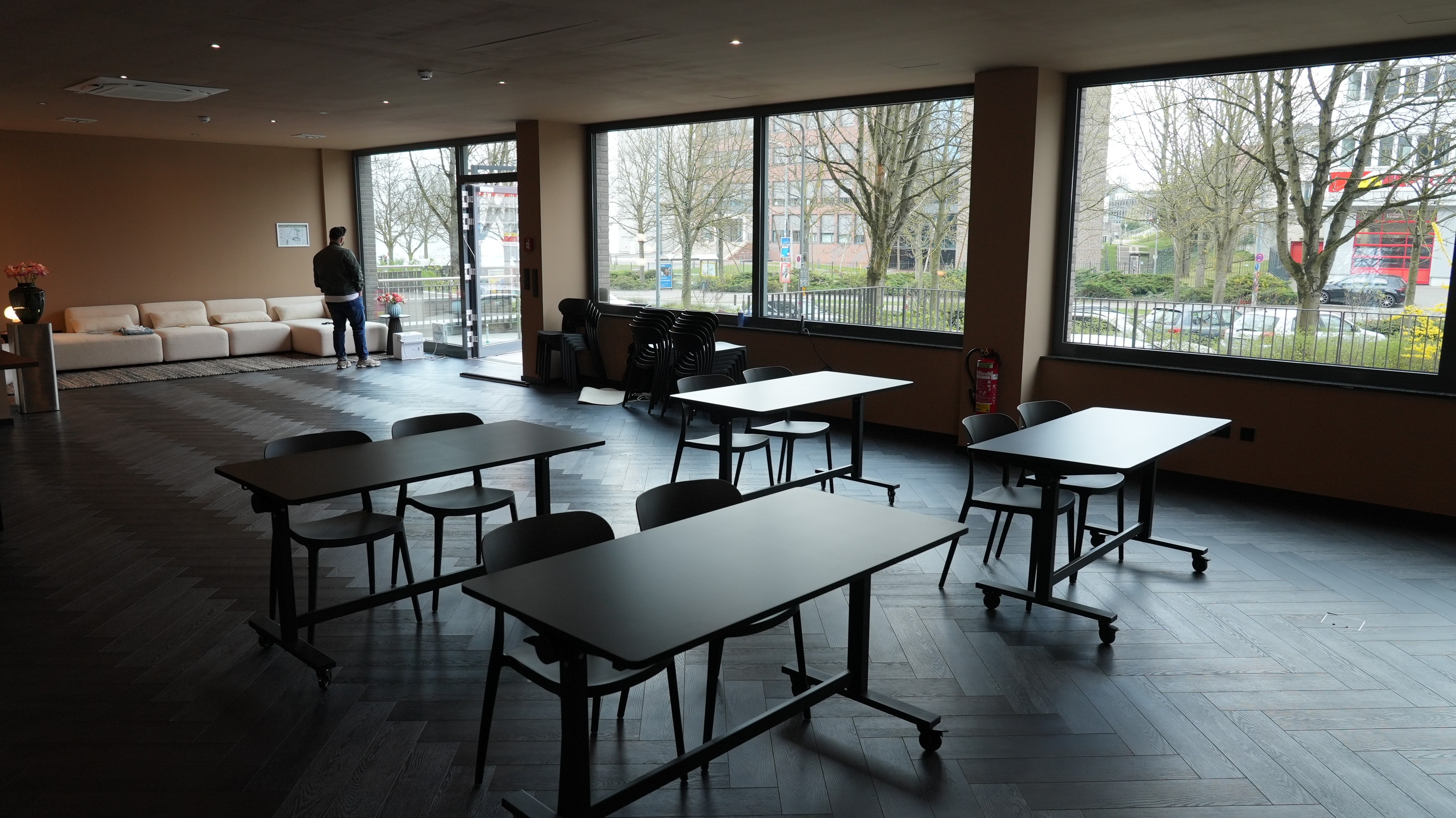 A person walks down a sunlit hallway with luggage.