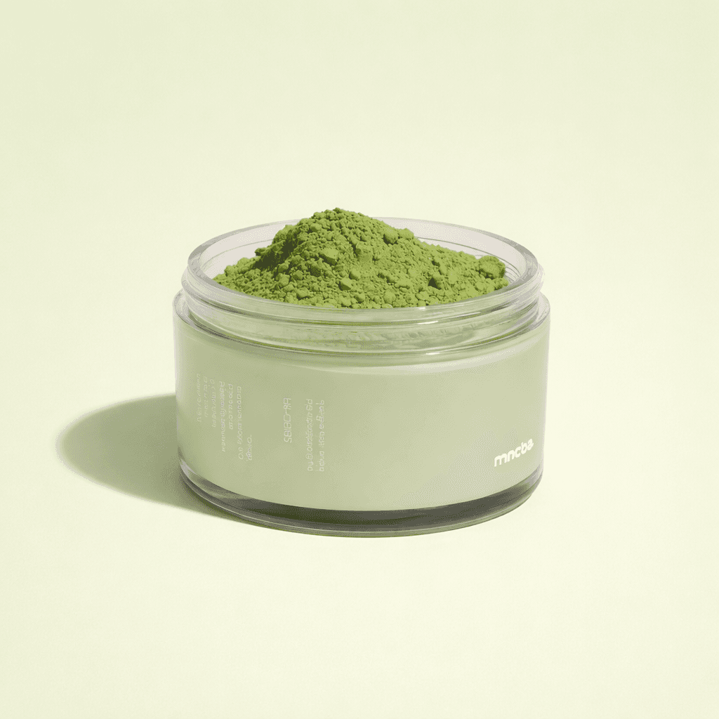 Open matcha powder tin with a bamboo whisk and loose matcha powder on a light stone surface