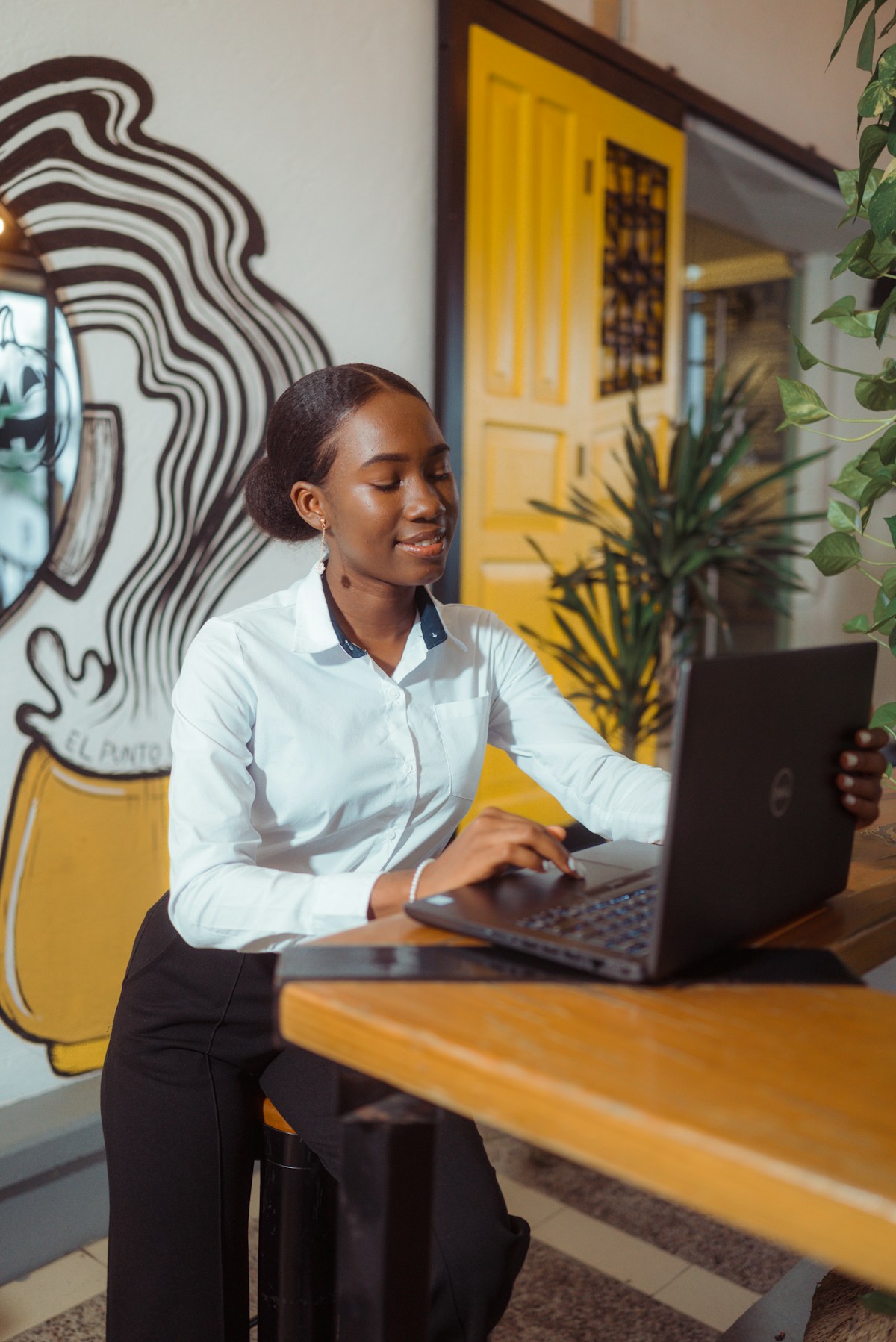 A woman working on a laptop at a wooden table