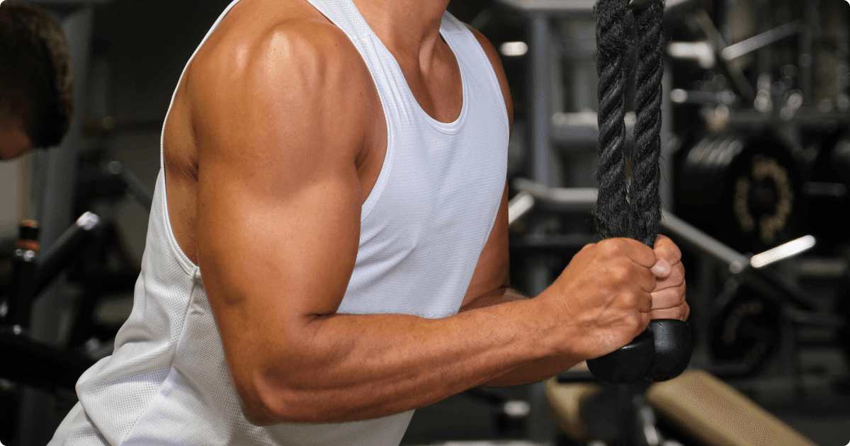 Close-up of a person working out in a gym, performing a triceps cable rope pushdown