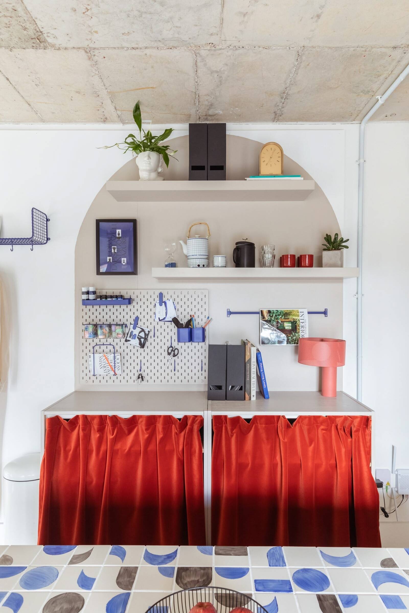 Colourful bespoke London office with red fabric curtains and a workshop area designed for organised creativity
