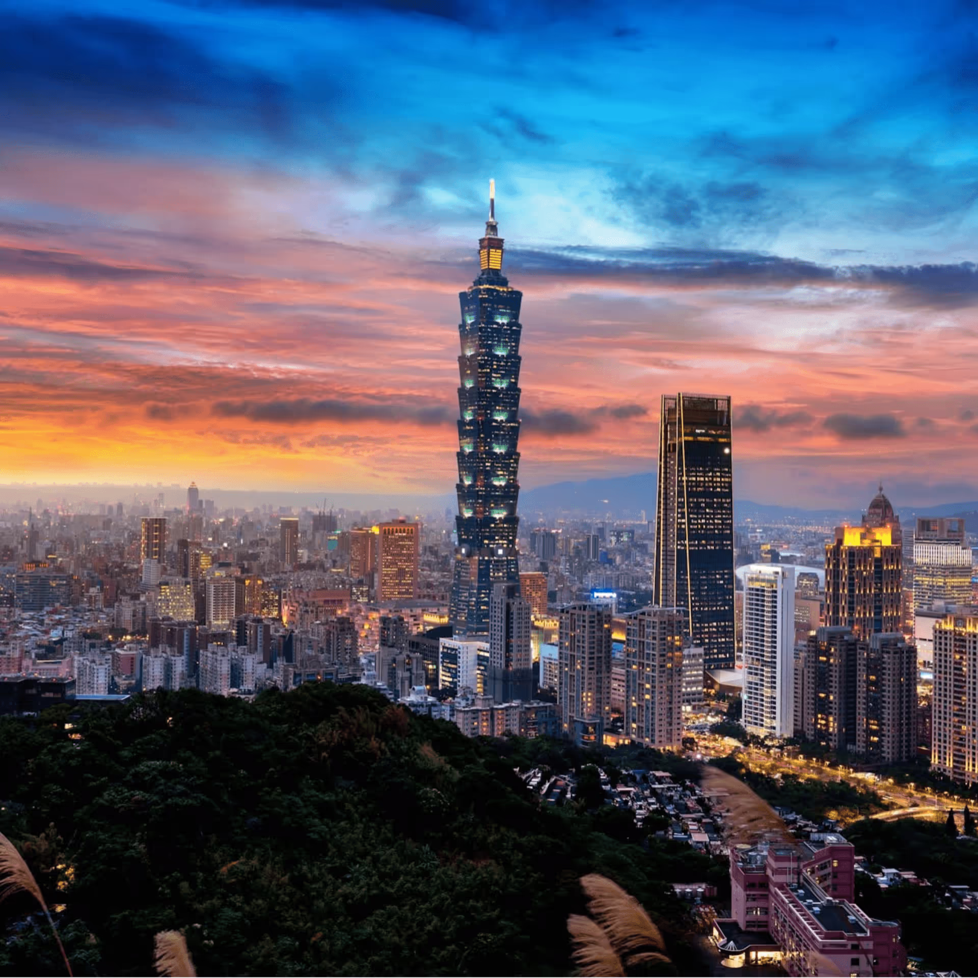 Taipei 101 skyscraper towering over a vibrant cityscape at sunset.