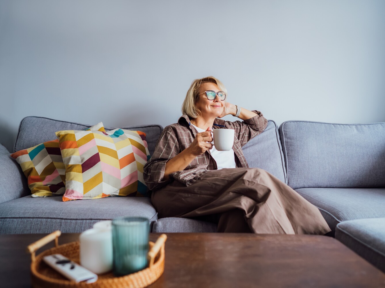 woman sitting on her couch to relax with a cup of tea after doing an at-home weight loss workout the day before