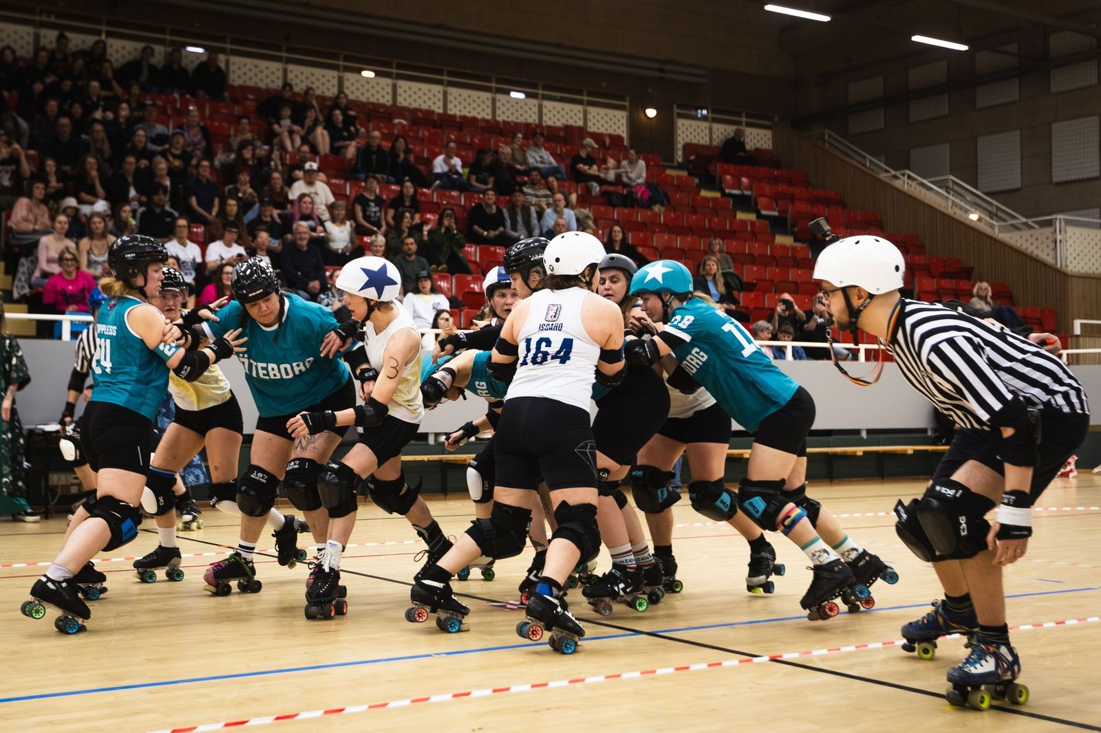 A group of roller derby players hugging after a game.
