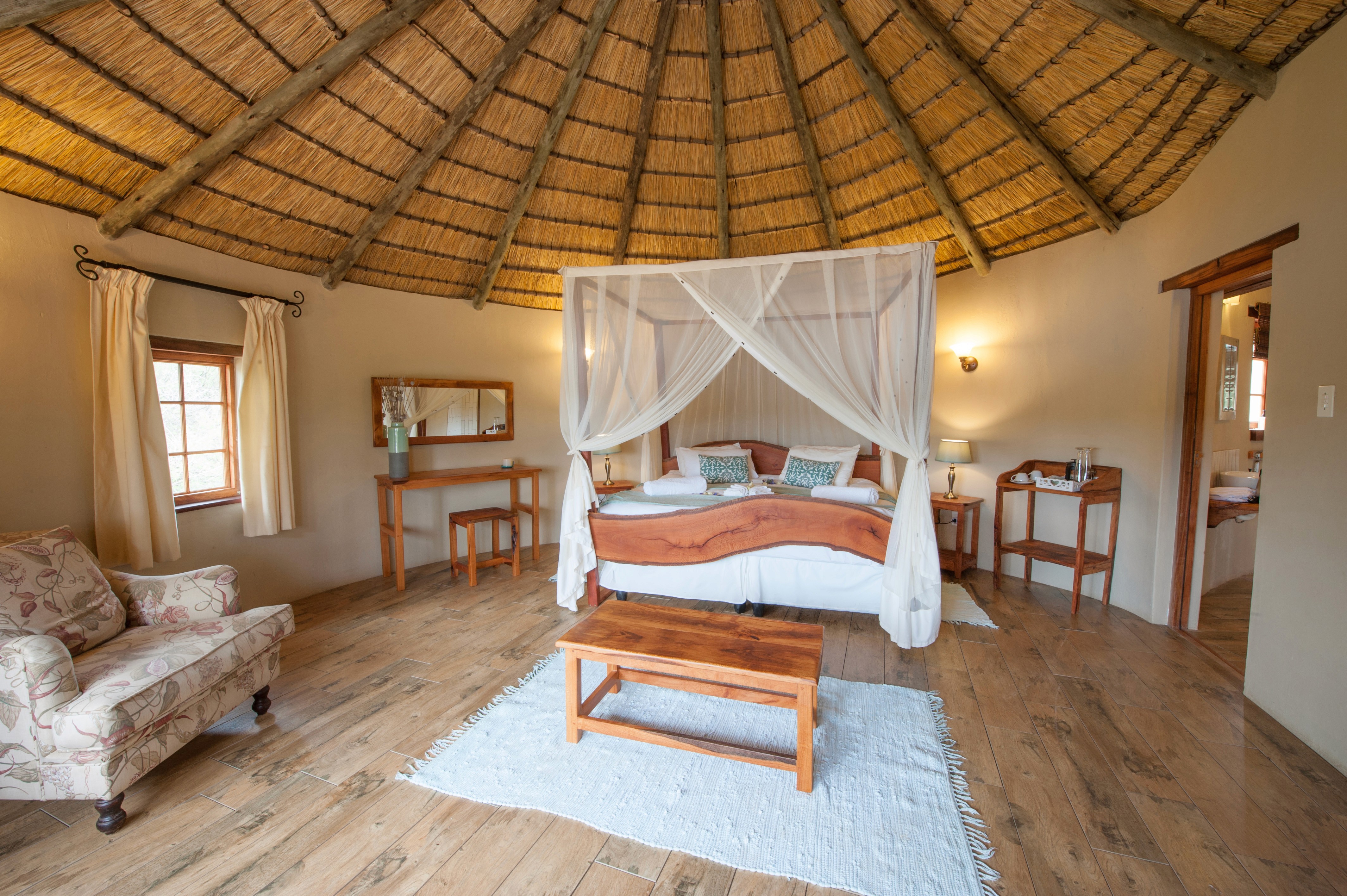 Ridsafari i Waterberg, Sydafrika. Stort och rymligt dubbelrum med vacker dubbelsäng omgiven av myggnät. Ljust och stort, ensuite badrum, på Signature Safari, ridresa till Afrika.