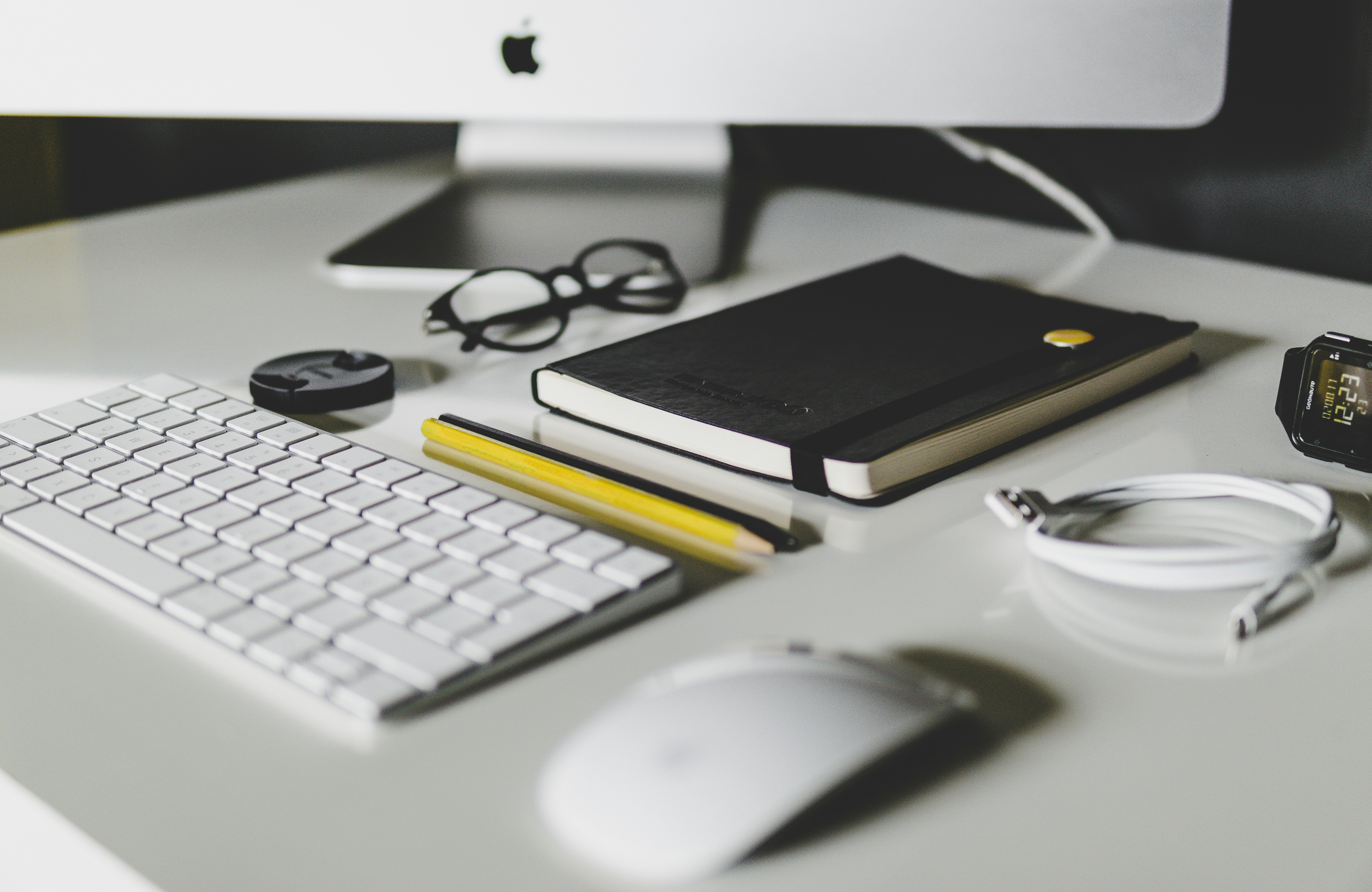 Modern workspace with computer, keyboard, notebook and glasses on a desk