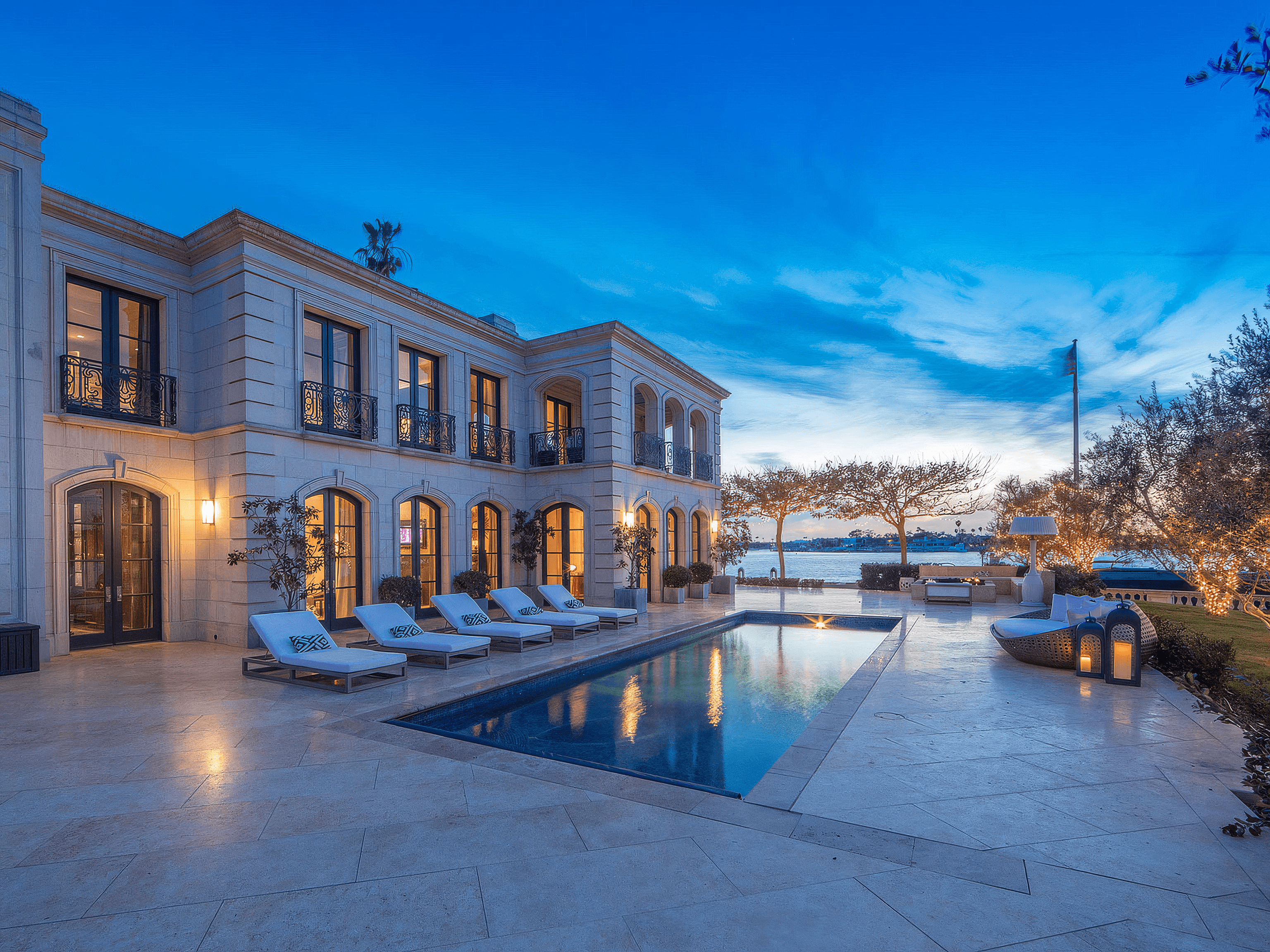 Mediterranean revival Newport Coast backyard with outdoor fireplace, pergola, and seating areas, designed by best Orange County home builder.