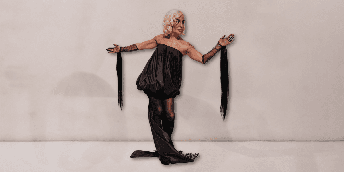 Elton Eilirjani, known as Hanko, poses in a dramatic black fashion piece with fringe, embodying strength and empowerment.