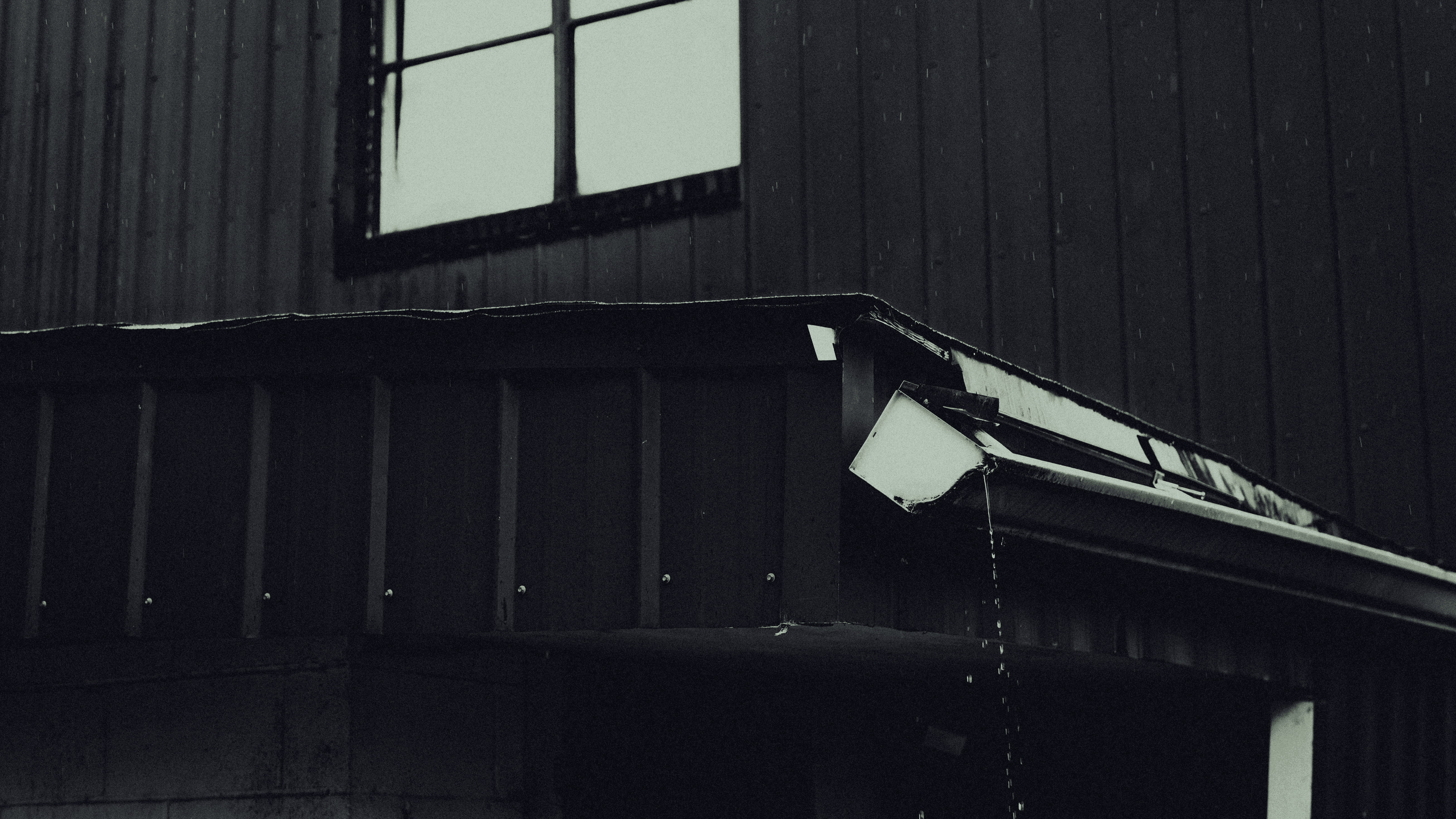 A broken rain gutter attached to a two story home struggles to handle water flow after a rain storm