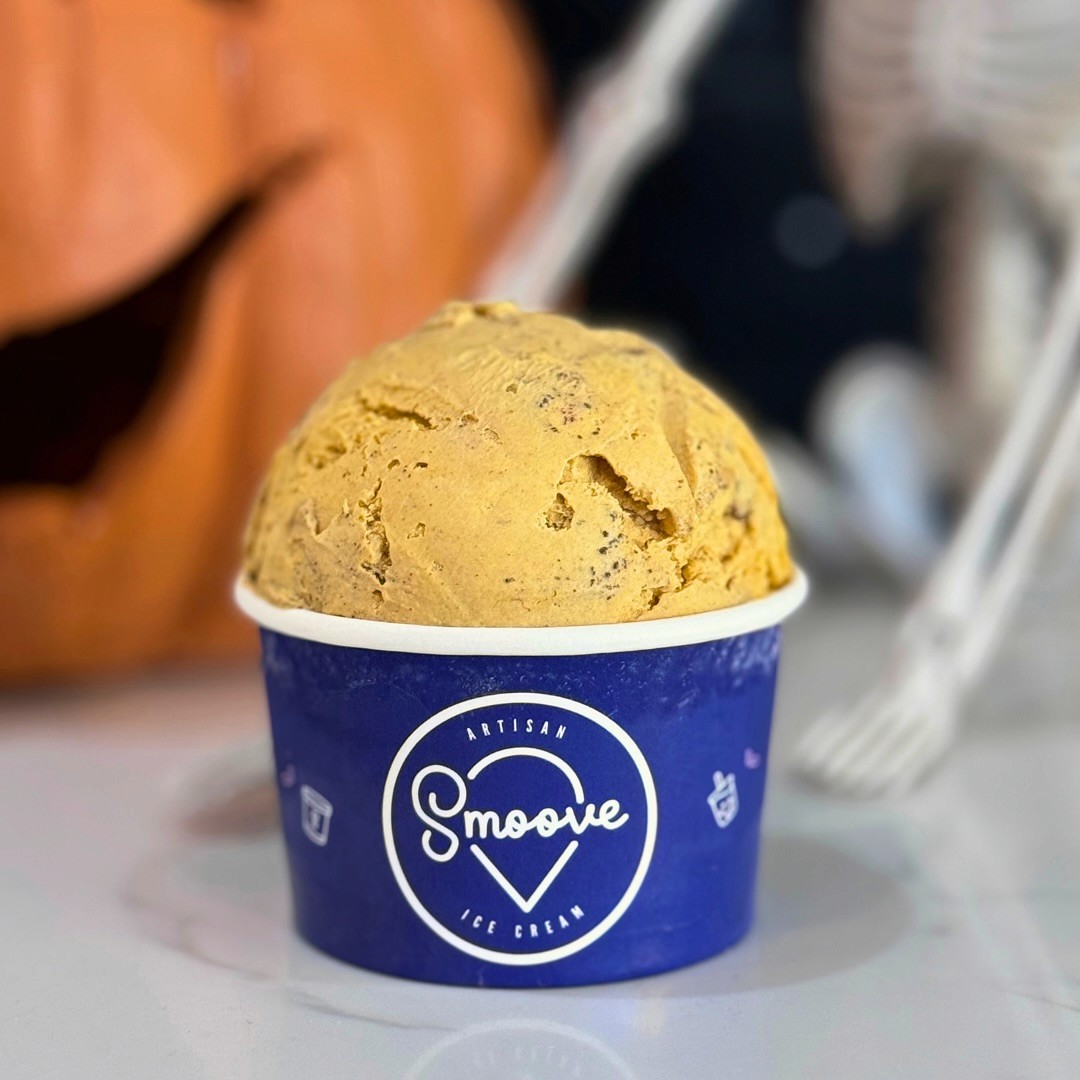 A scoop of golden-hued ice cream served in a vibrant blue Smoove-branded cup, radiating creamy indulgence. The bold color and rich flavor highlight the unique and innovative desserts at Smoove.