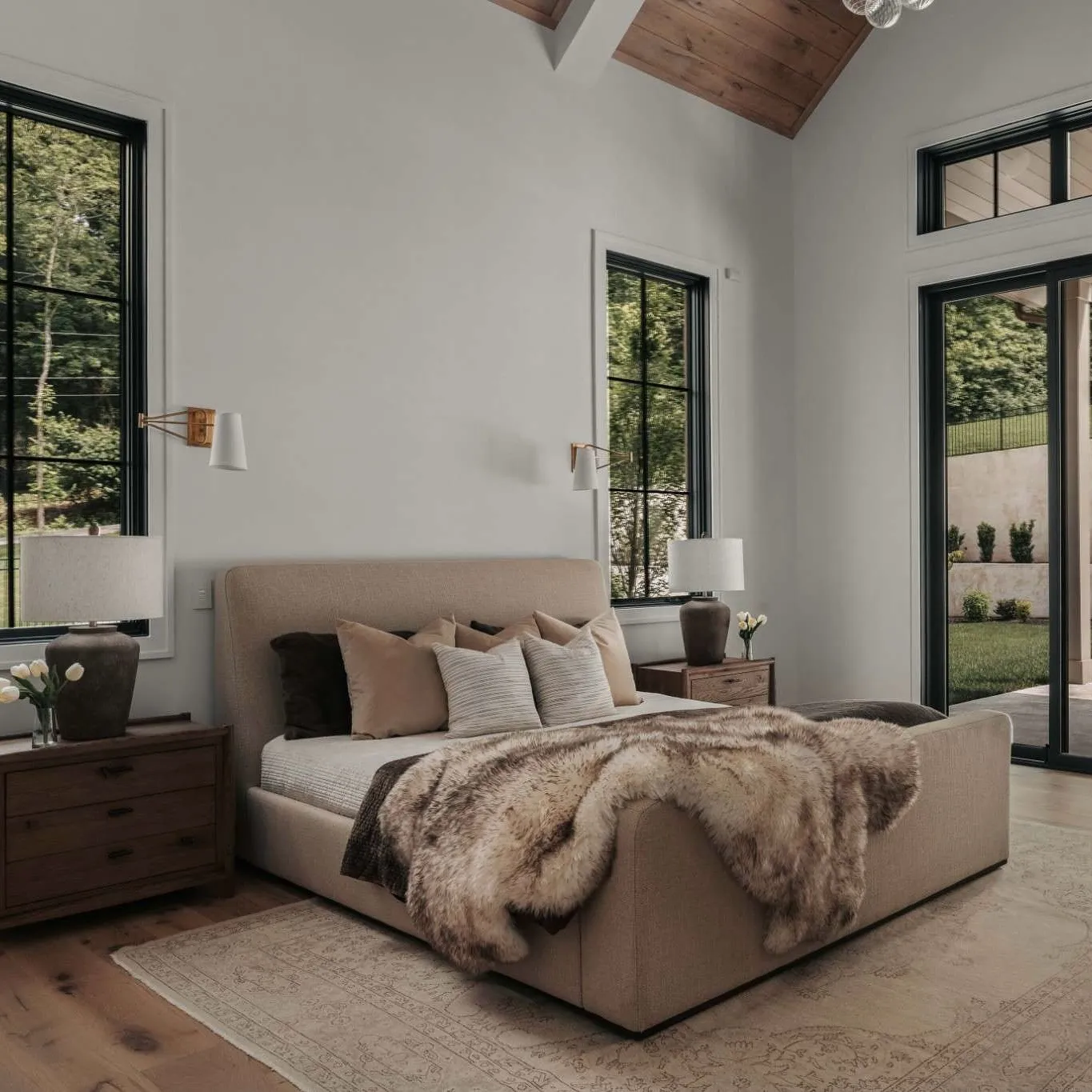 A serene bedroom with a bed, nightstand, and large windows.