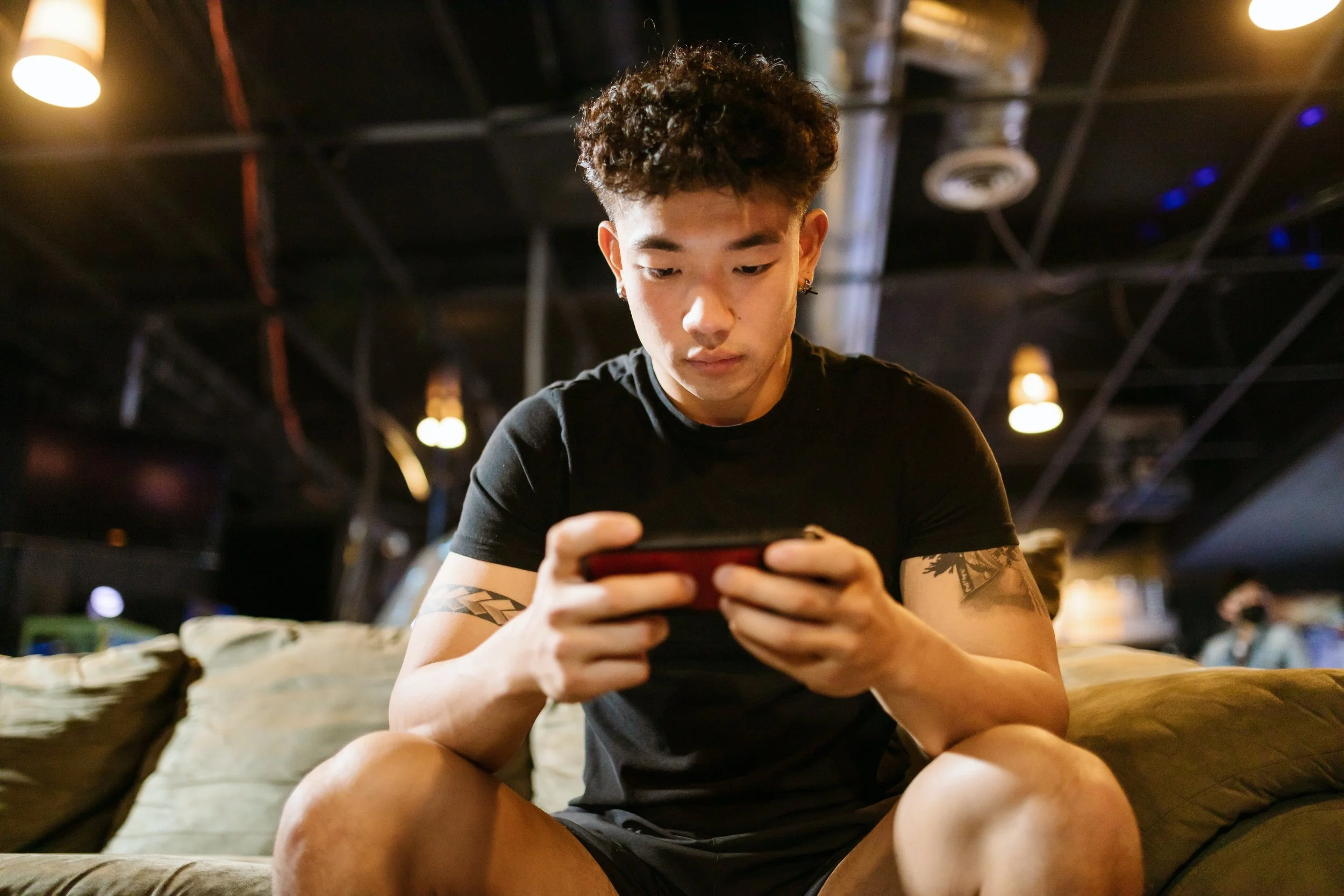 A young man sits on his phone, pondering something