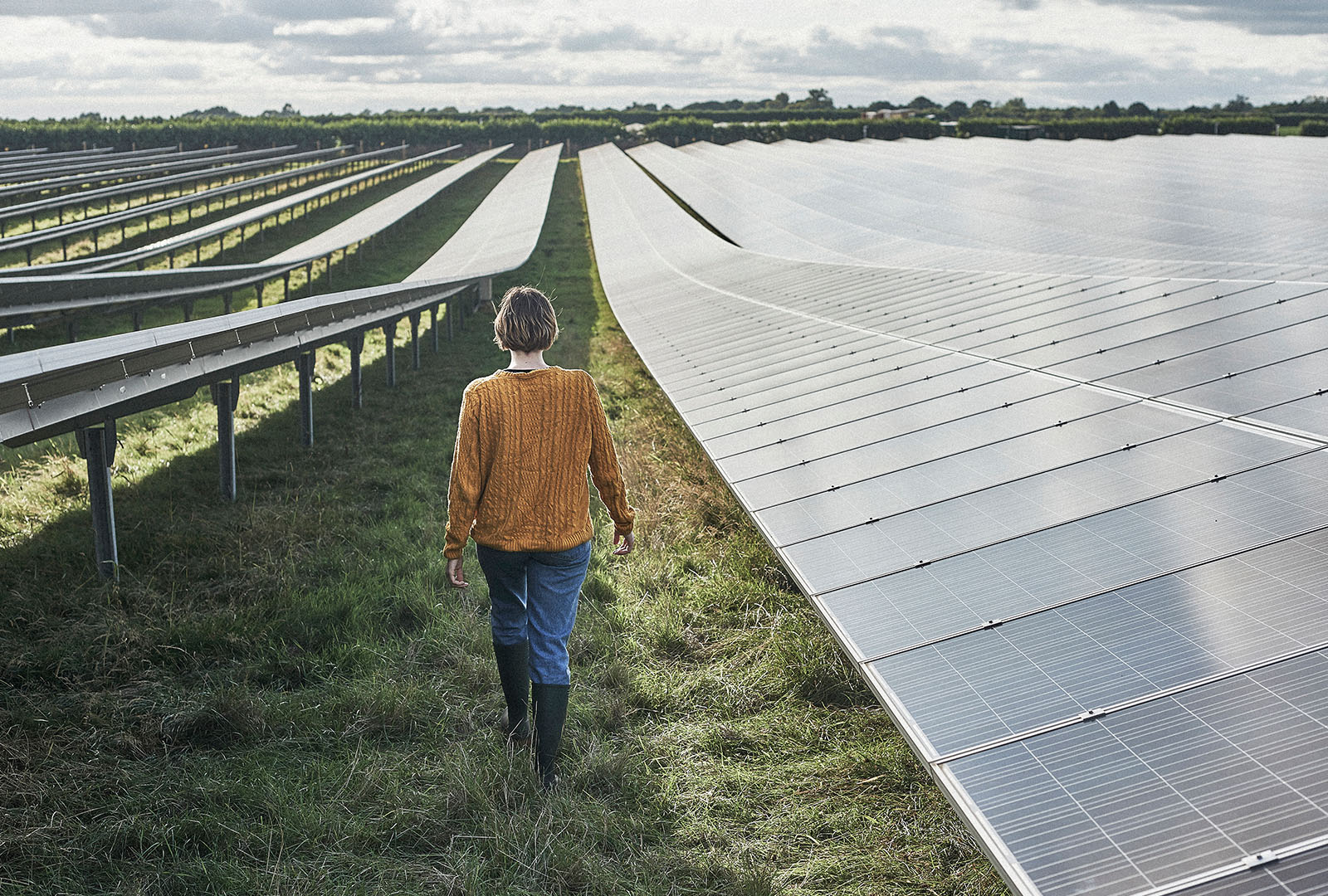 Woman walking through a field with a row of solar panels