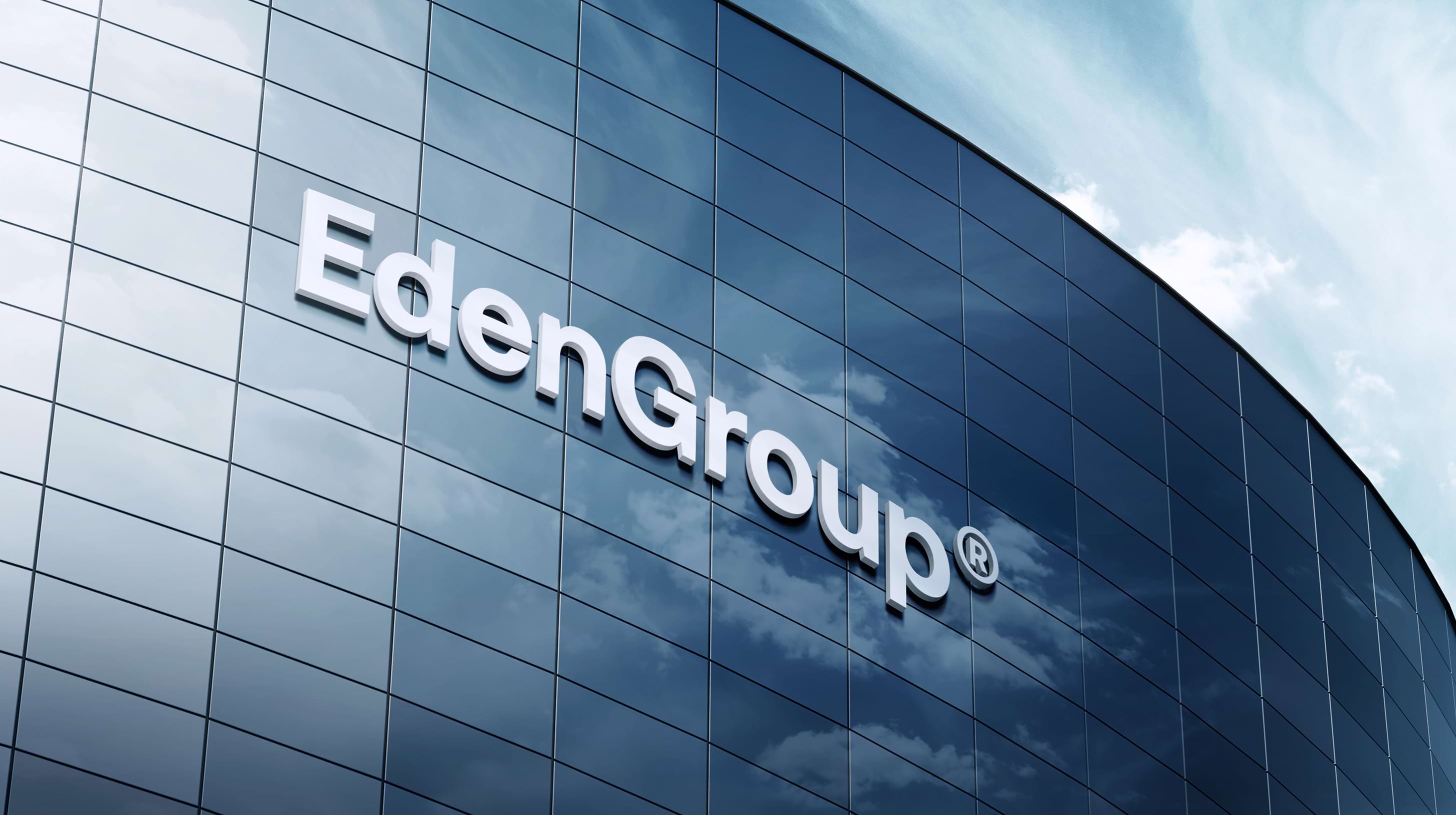 Curved glass building facade with "EdenGroup®" in bold white letters, set against a partly cloudy blue sky, conveying a modern and professional tone.