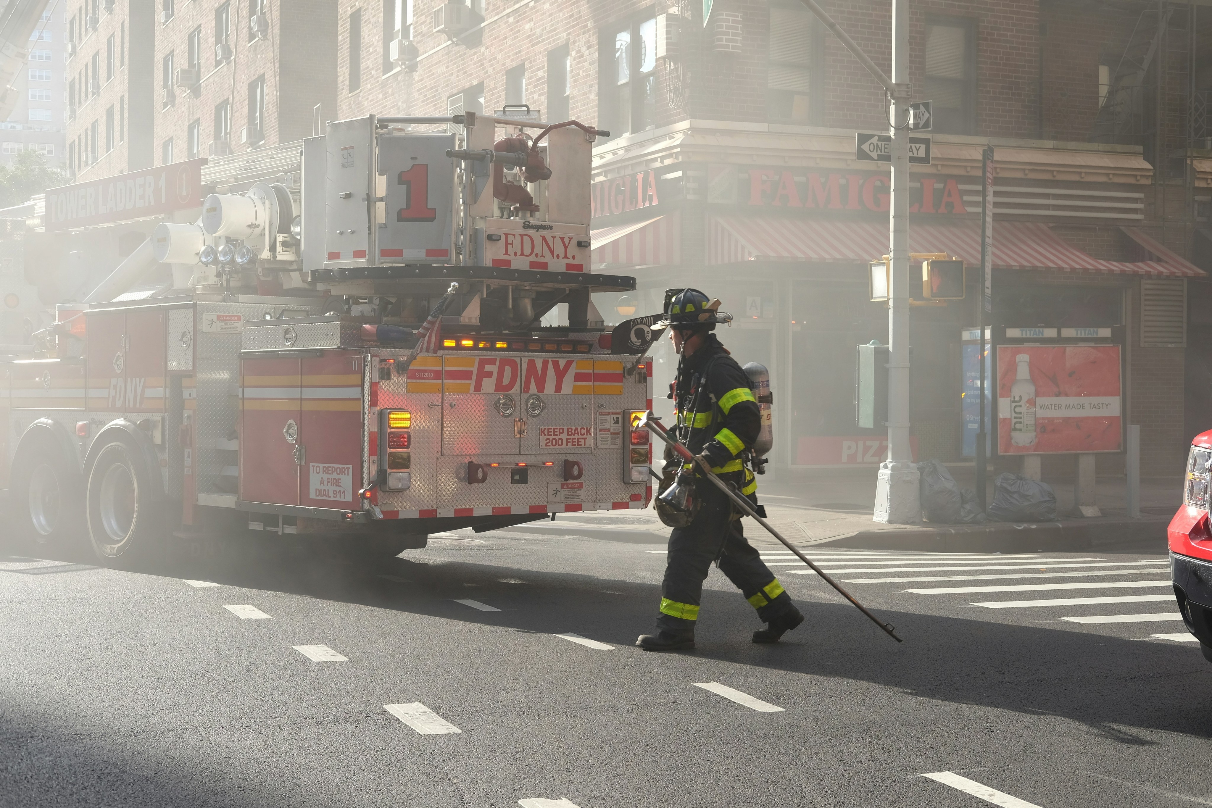 man in green and black jacket holding black stick standing on pedestrian lane during daytime