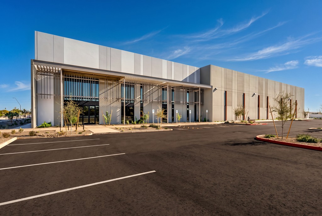 Newly completed industrial building with metal sunshades and an empty parking lot