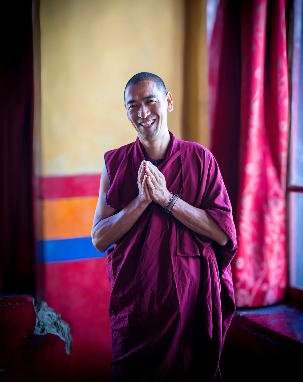 Monje sonriente saludando con las manos juntas en un monasterio de Ladakh