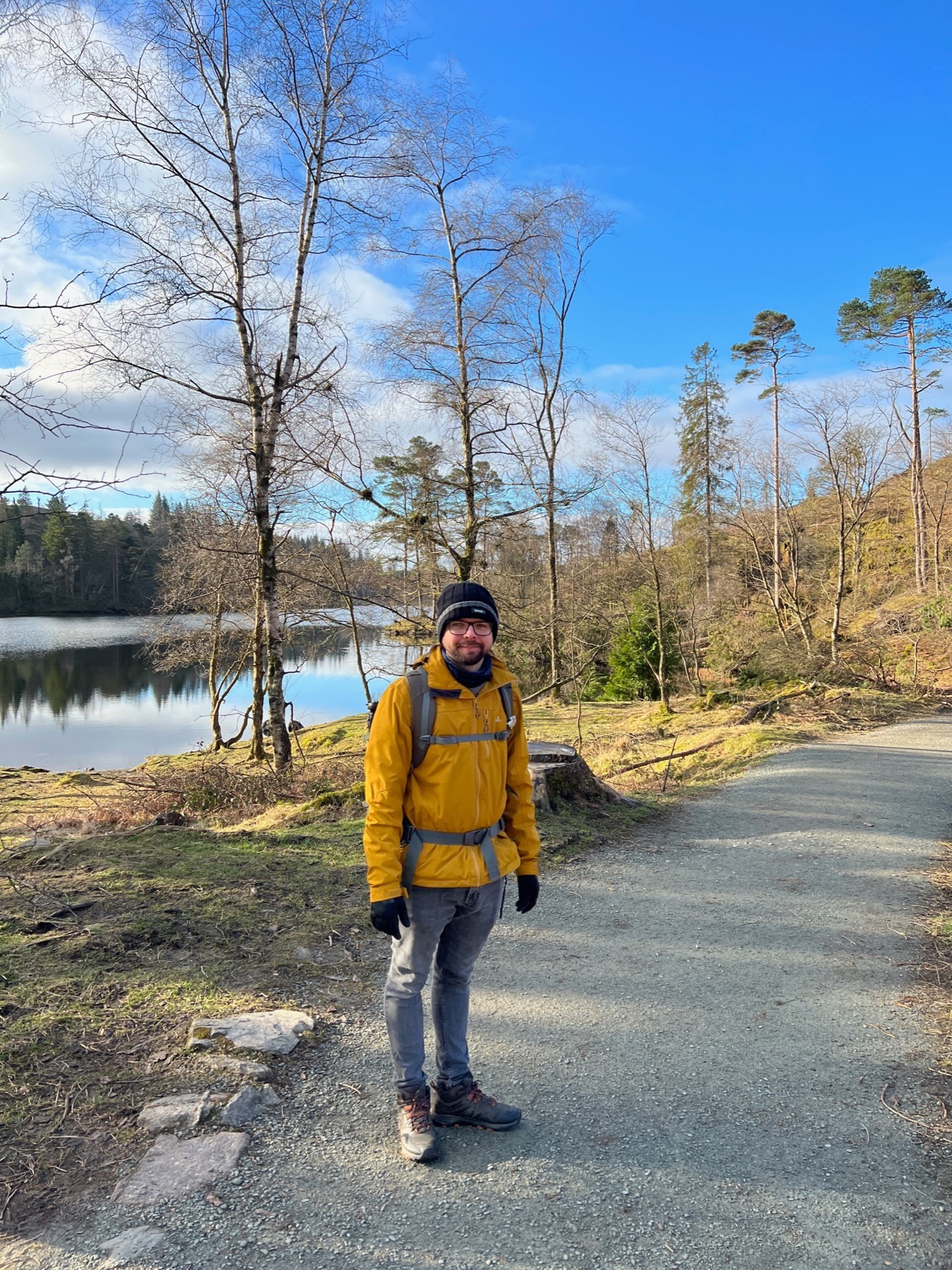 Martin stood at Tarn Hows in his yellow jacket and winter hat.