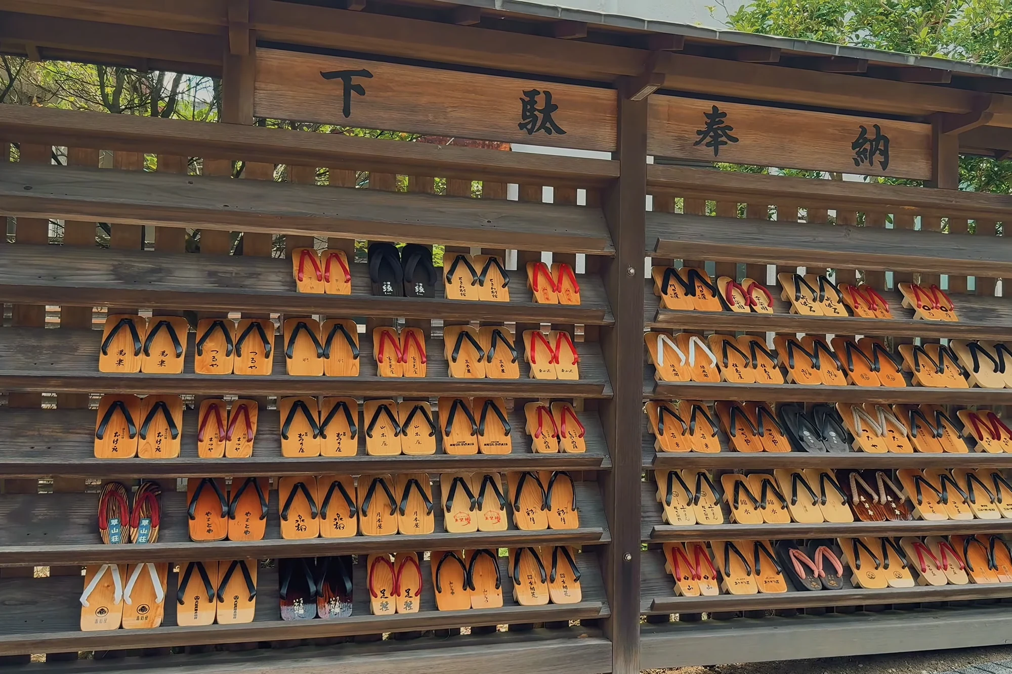 A wall of wooden geta sandals racked in numbered rows at a Kinosaki bathhouse.