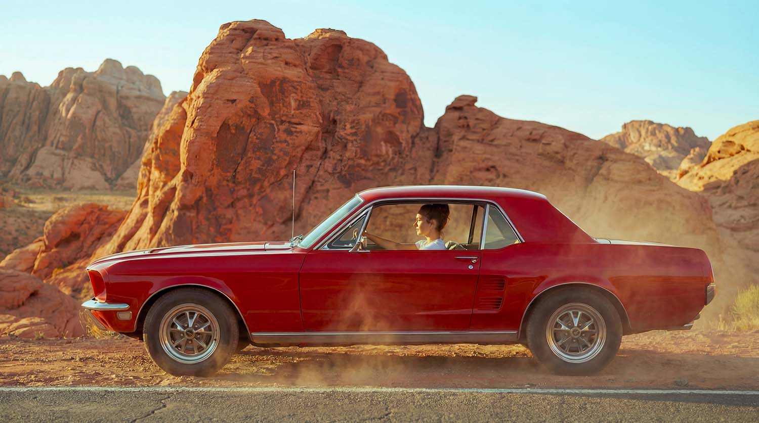 Carro vermelho estacionado em paisagem rochosa no teaser da coleção feminina ARMYBR.