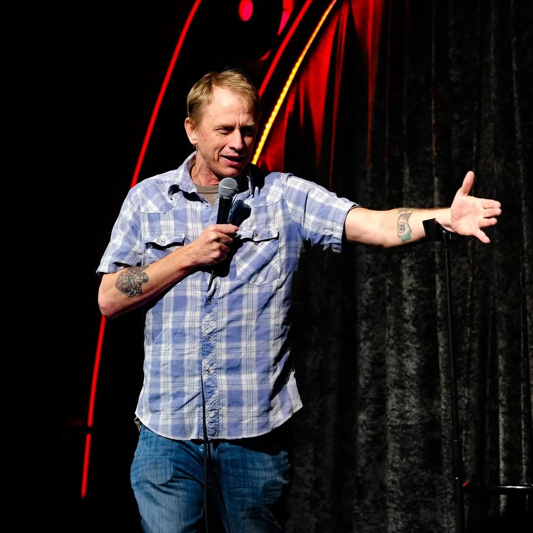 Davey Wester performing Stand Up Comedy and holding his arm out