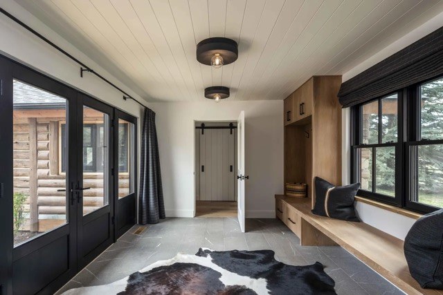 Mudroom with black-framed glass doors, a built-in bench, and a cowhide rug