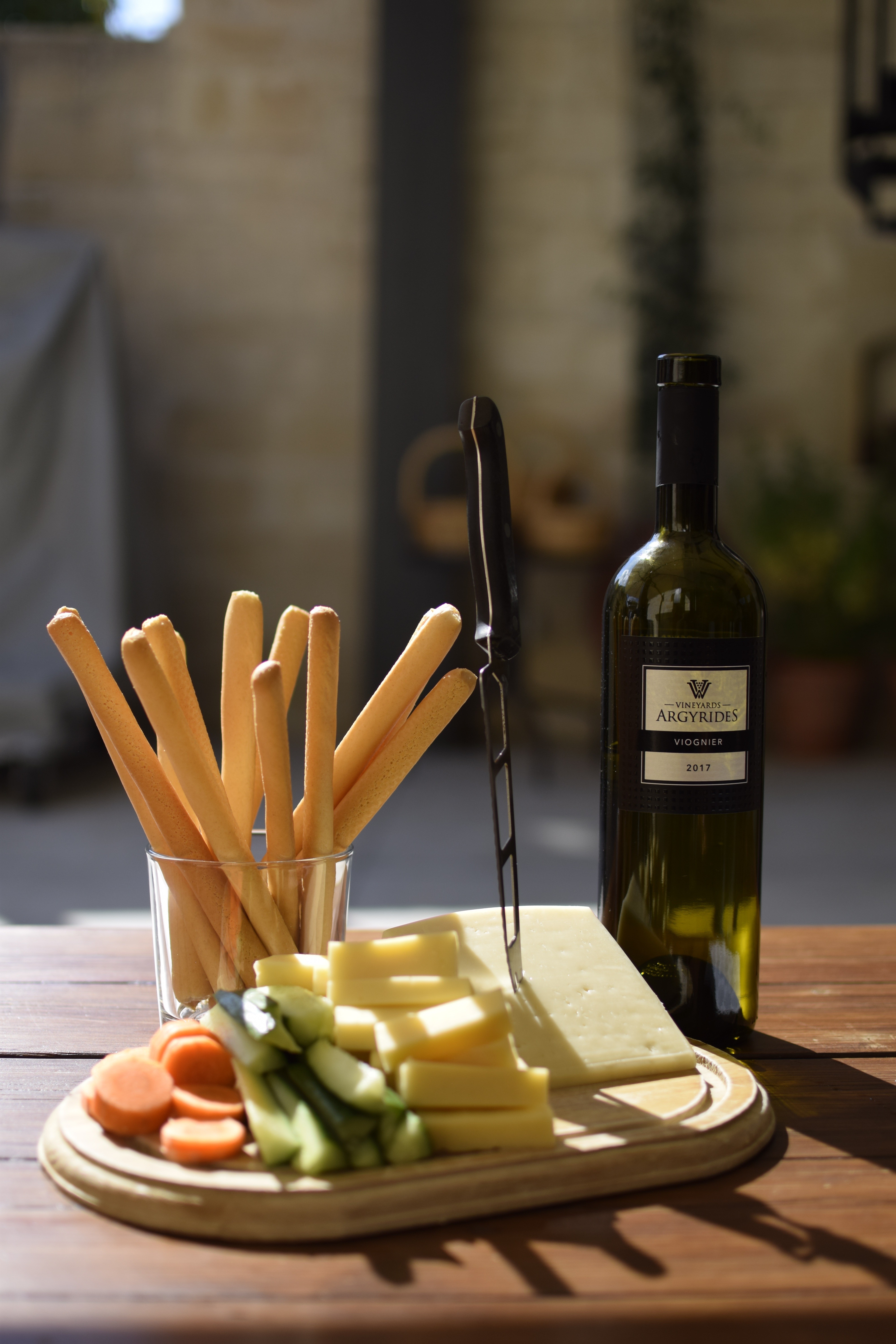 Bouteille de vin avec fromage, gressins et légumes frais sur table en bois