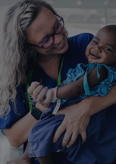 Volunteer holding a baby while smiling