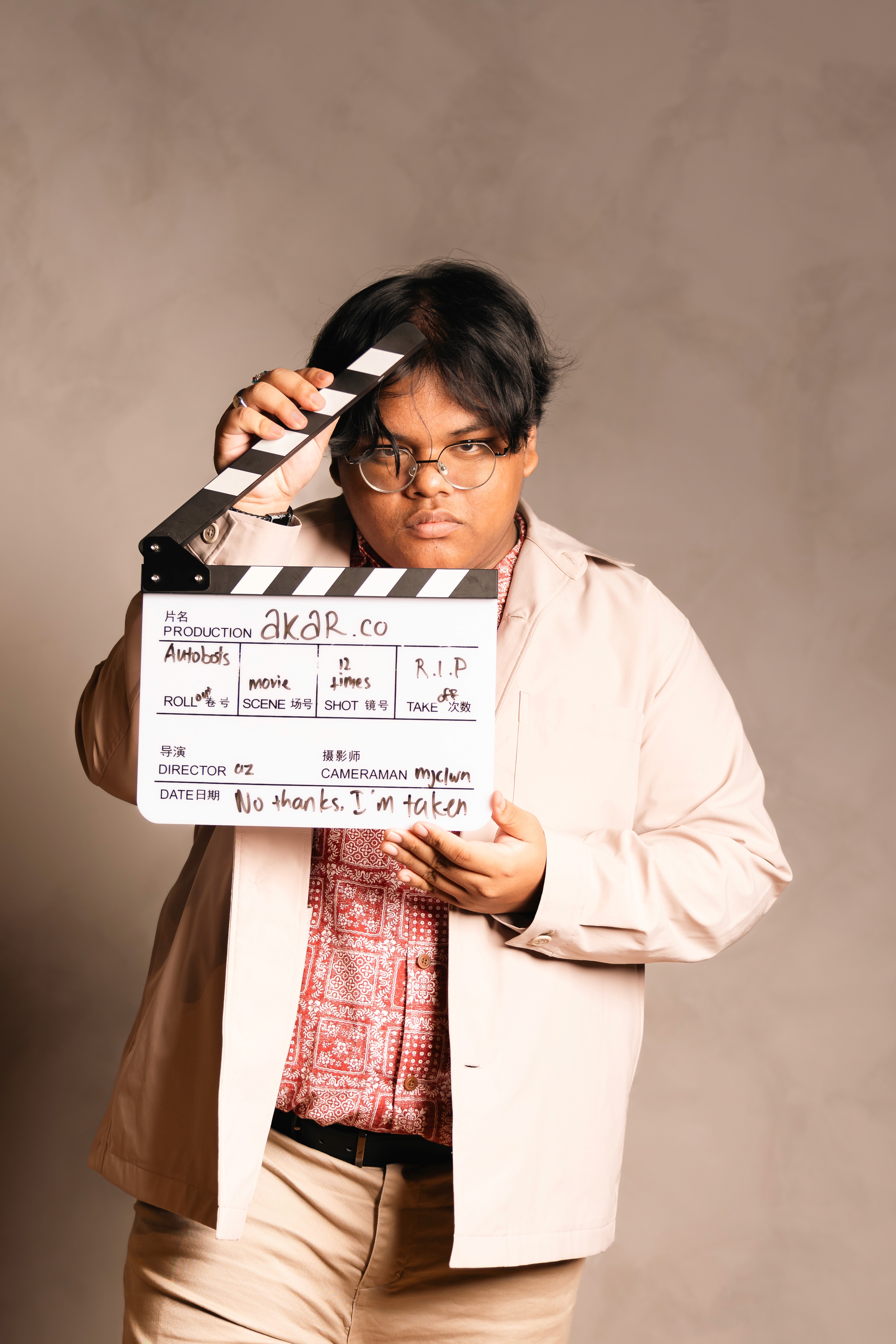 aküma posing with a clapper board for a stylised portrait