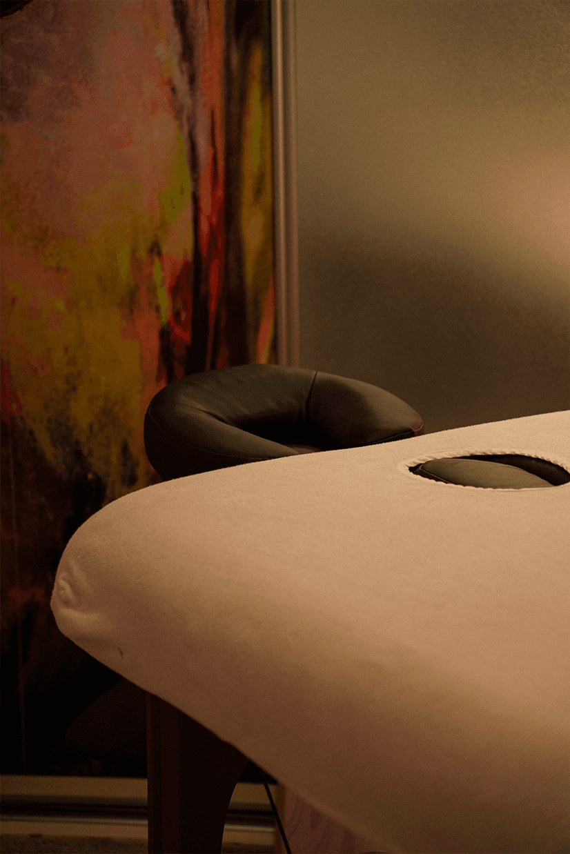 A person with curly hair sits at a desk, working on a laptop in a cozy, well-lit environment.