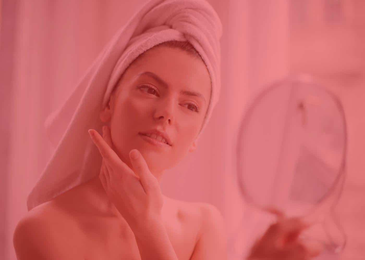 Is red light therapy safe? Woman checking her skin in a hand mirror