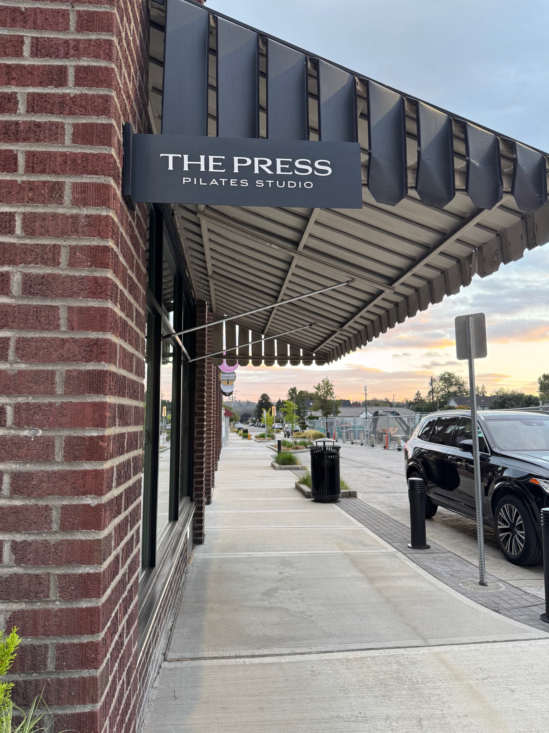 Exterior blade sign for a Pilates studio on a brick heritage building