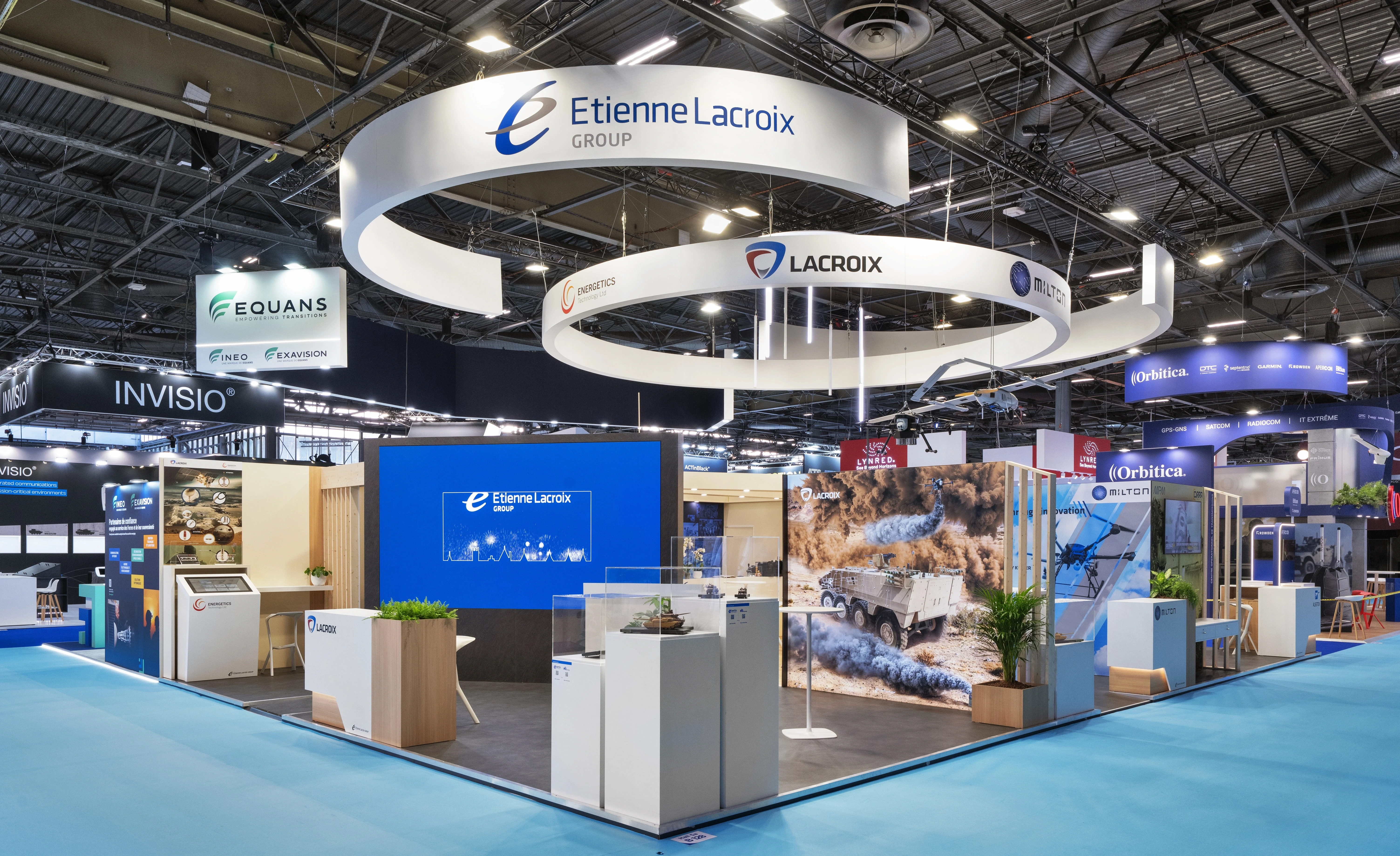 Stand Etienne Lacroix Group défense conçu par EXPACE à Eurosatory 2026 — double anneau suspendu LACROIX, Alsetex et Milton, vitrines produits et visuels d'autoprotection véhicule