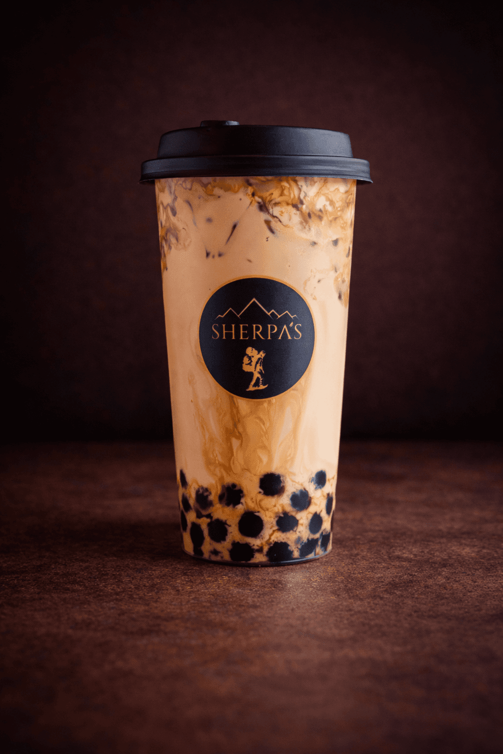 Iced Boba Latte with tapioca pearls in a Café Sherpa's to-go cup at Brookfield WI café. Double espresso over cold milk, a coffee and boba hybrid.