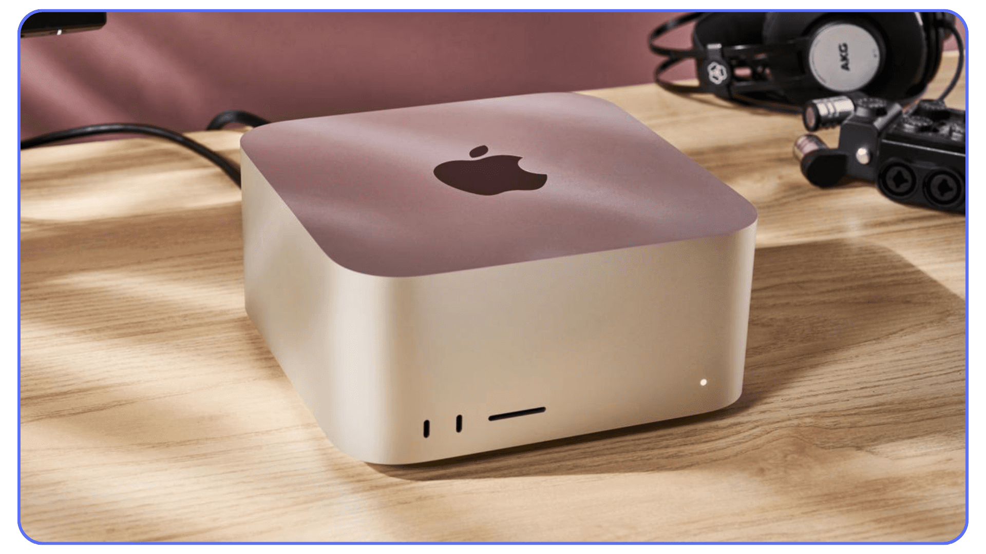 Apple Mac Studio desktop on wooden desk beside headphones and cables
