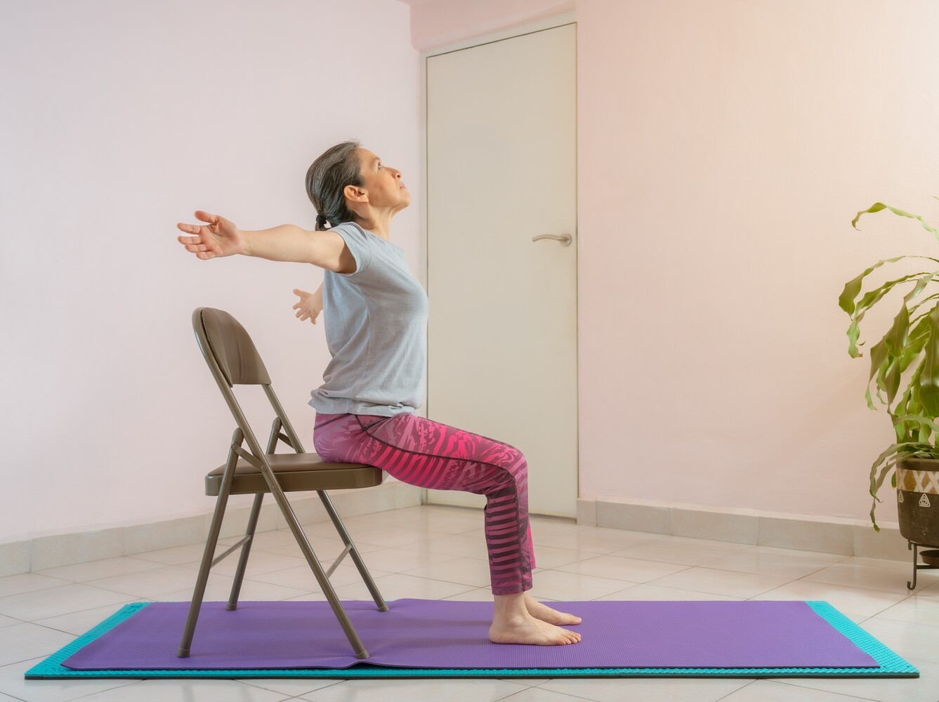 mature woman doing a chair exercise for weight loss in her home workout studio