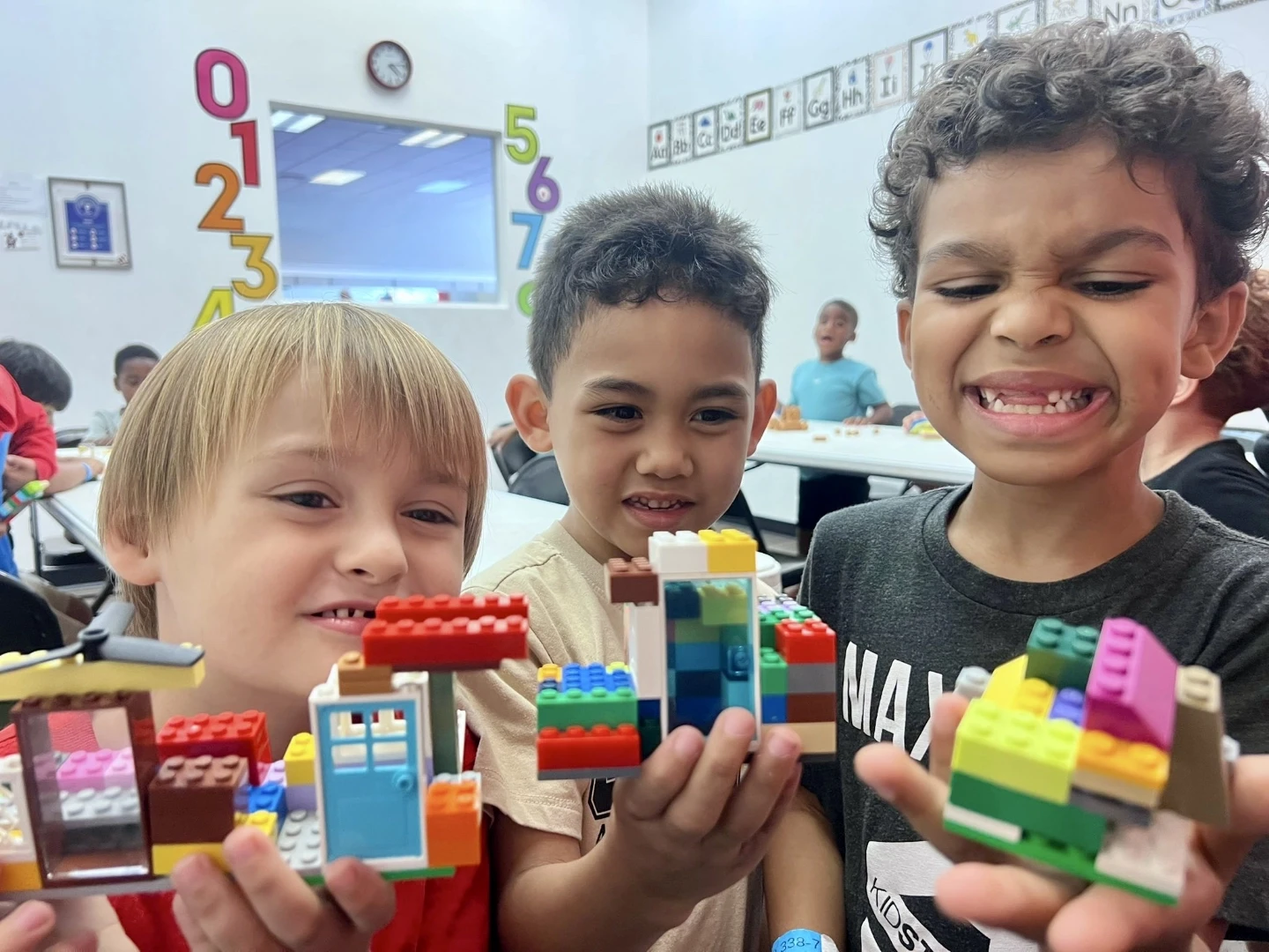 Three student showing legos they've built.