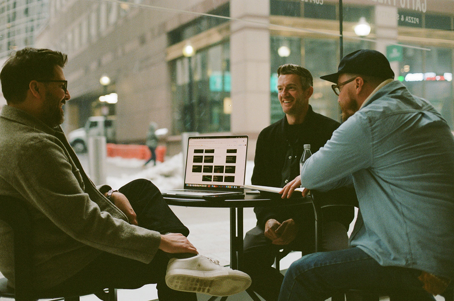 Two people focus on a laptop screen in a collaborative office setting. 