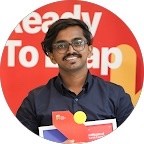 Portrait of a man with medium-length dark hair and a white shirt, set against a neutral background.