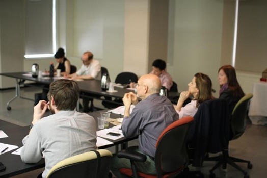 A photo of a group of people sitting at some desk and listening to a lecture.