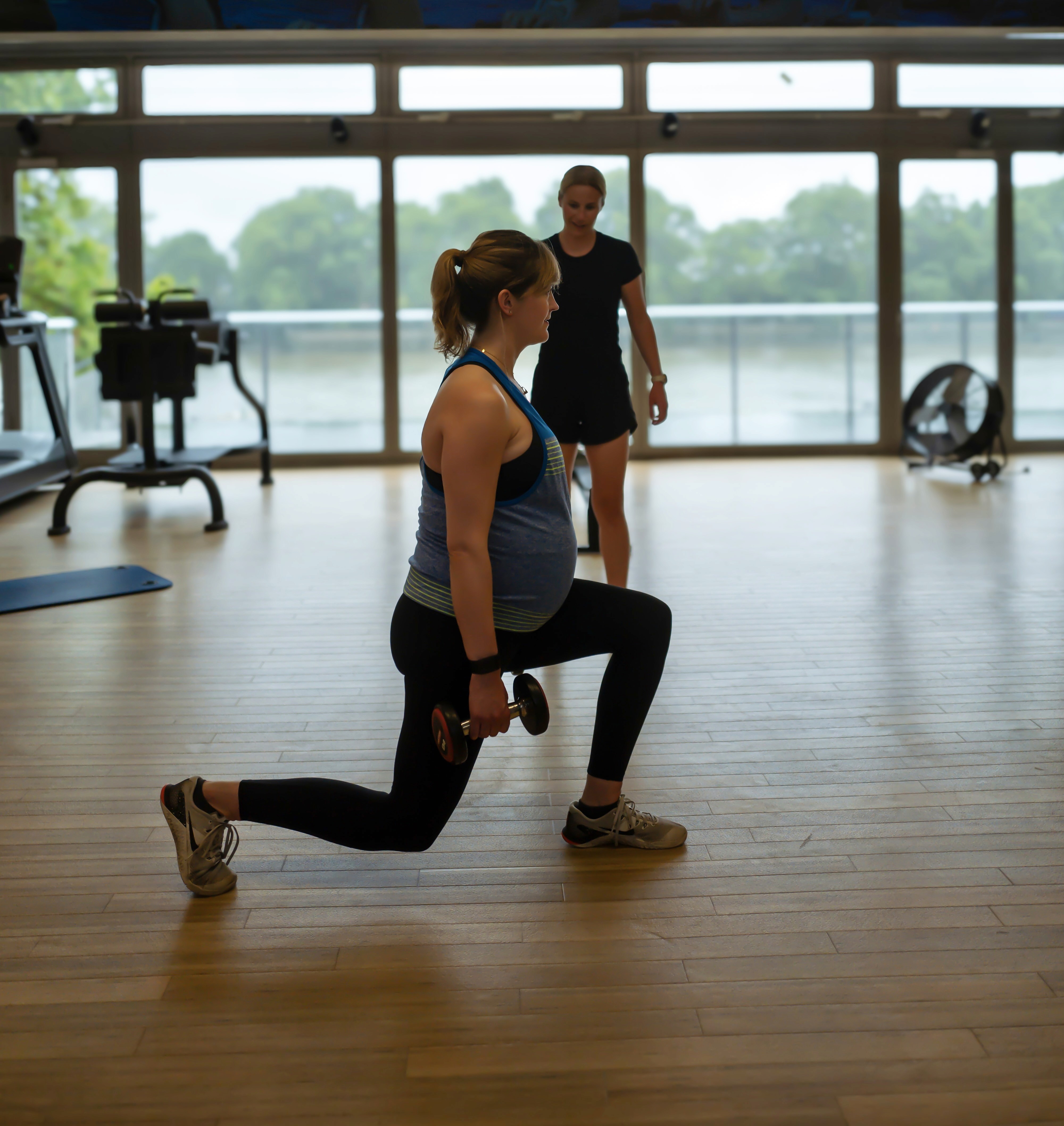 Personal trainer helping antenatal client with workout