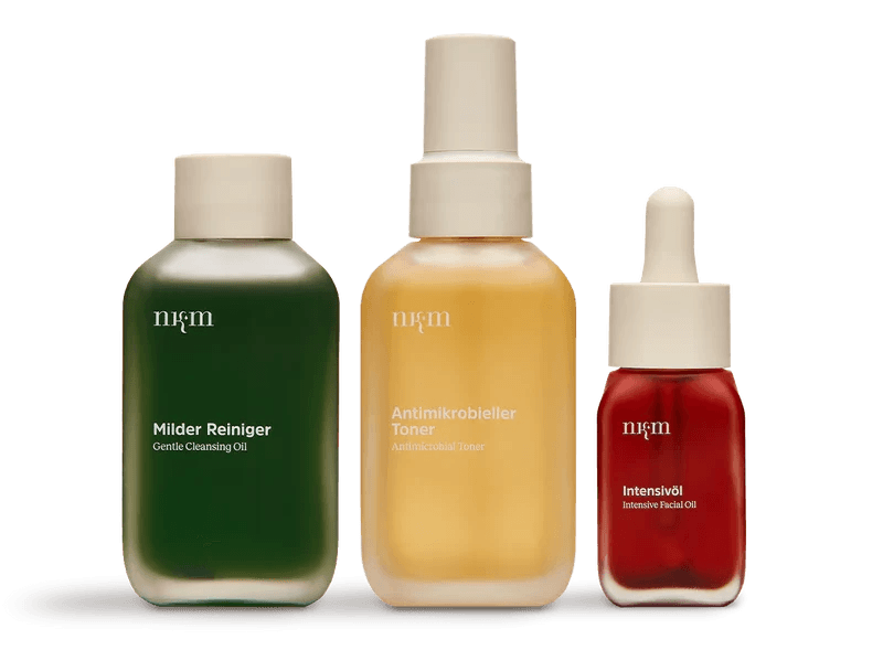 Three skincare bottles: green cleansing oil, yellow toner, red facial oil.