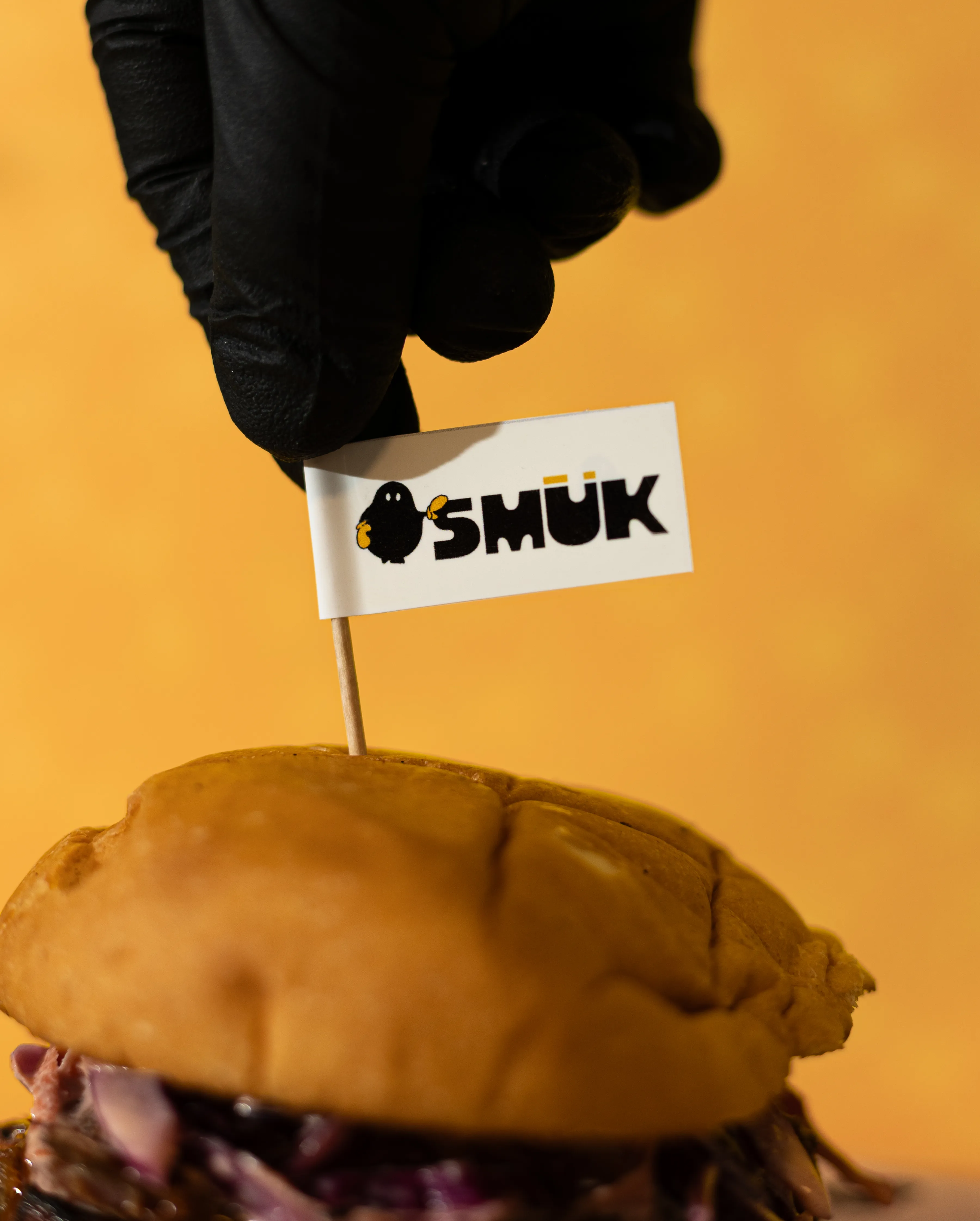Mano ajustando bandera en hamburguesa de pulled porkMano ajustando bandera en hamburguesa de pulled pork
